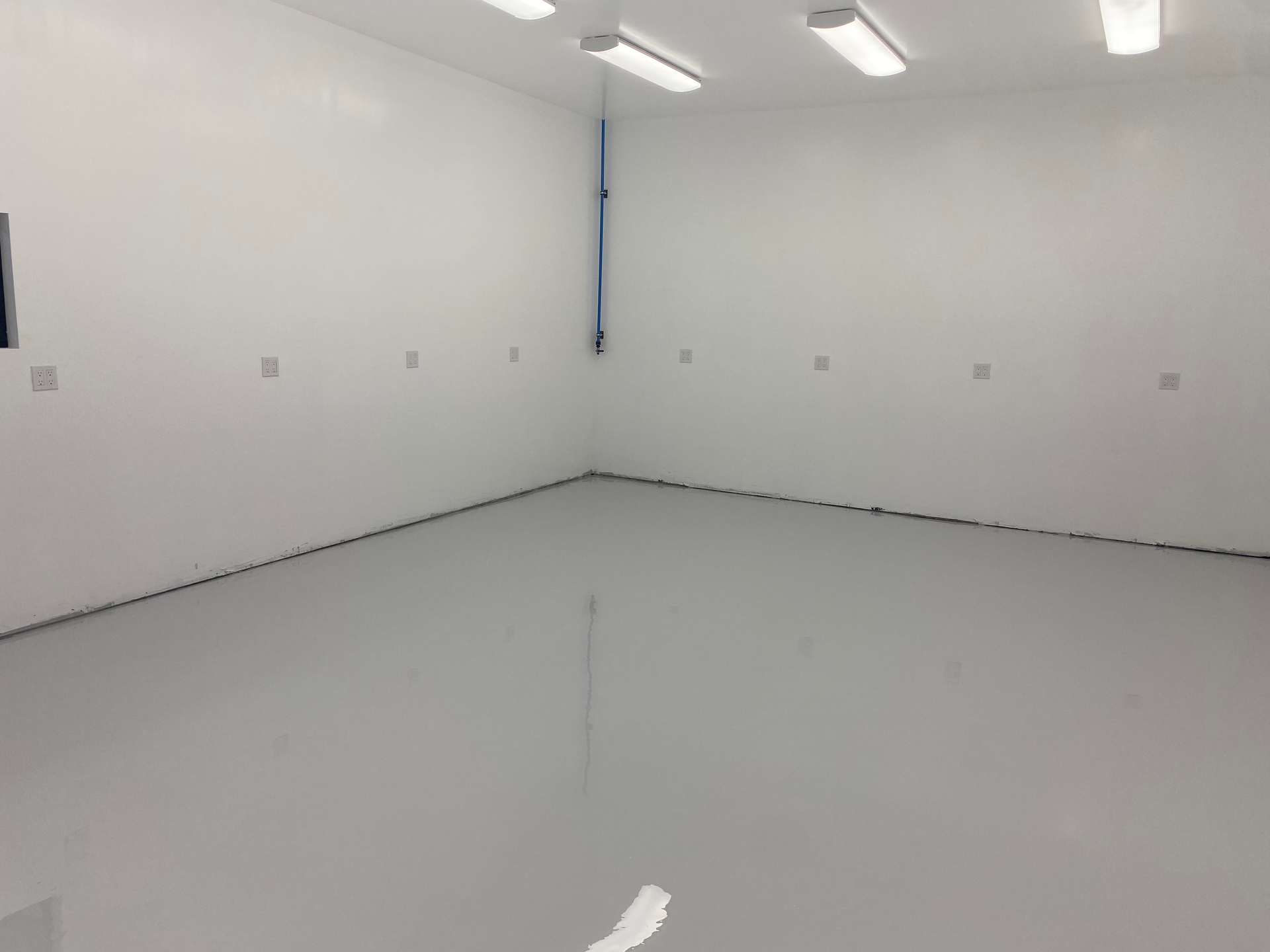 An empty room with white walls and a gray floor