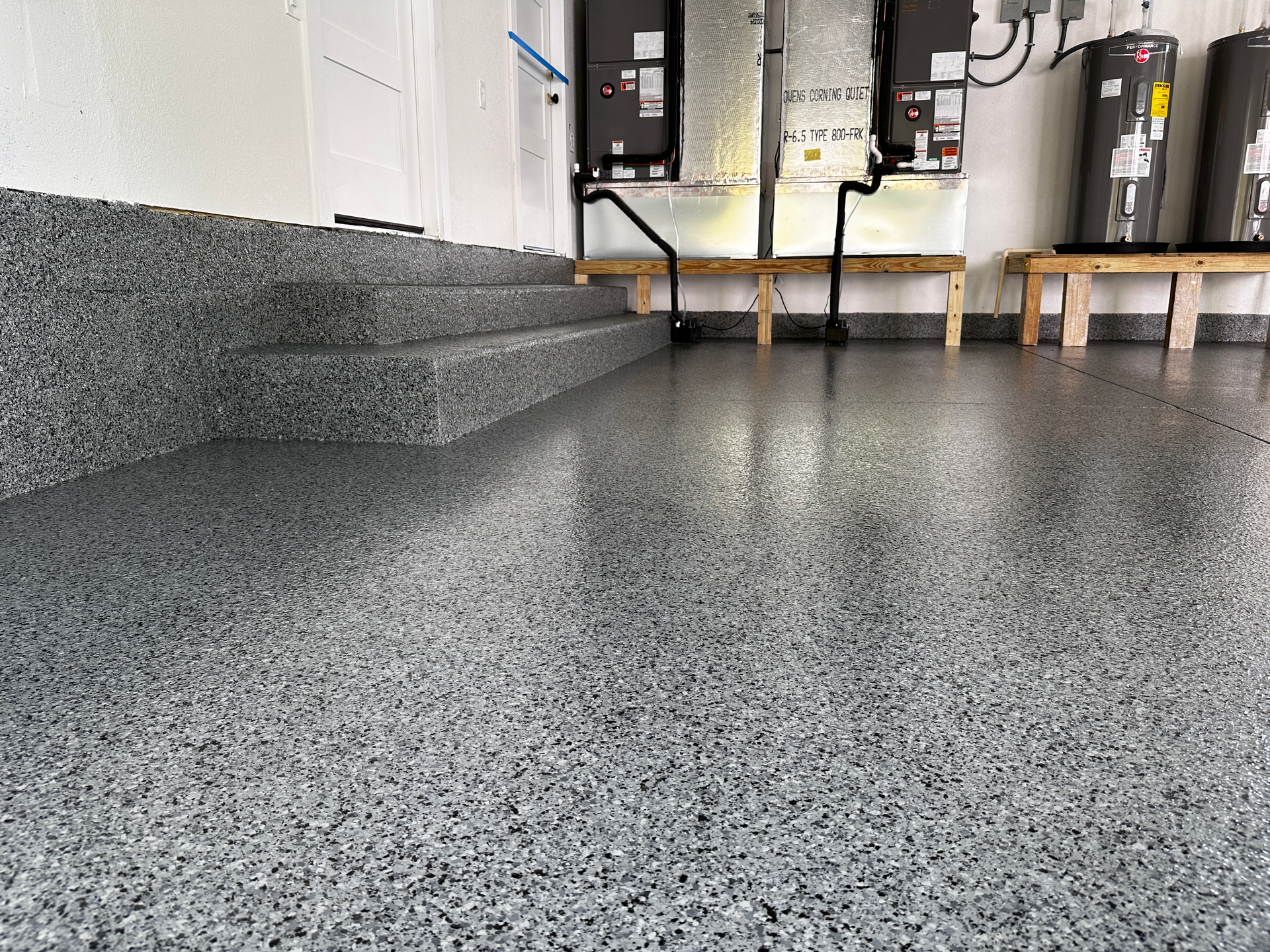 A garage with a gray concrete floor and stairs.