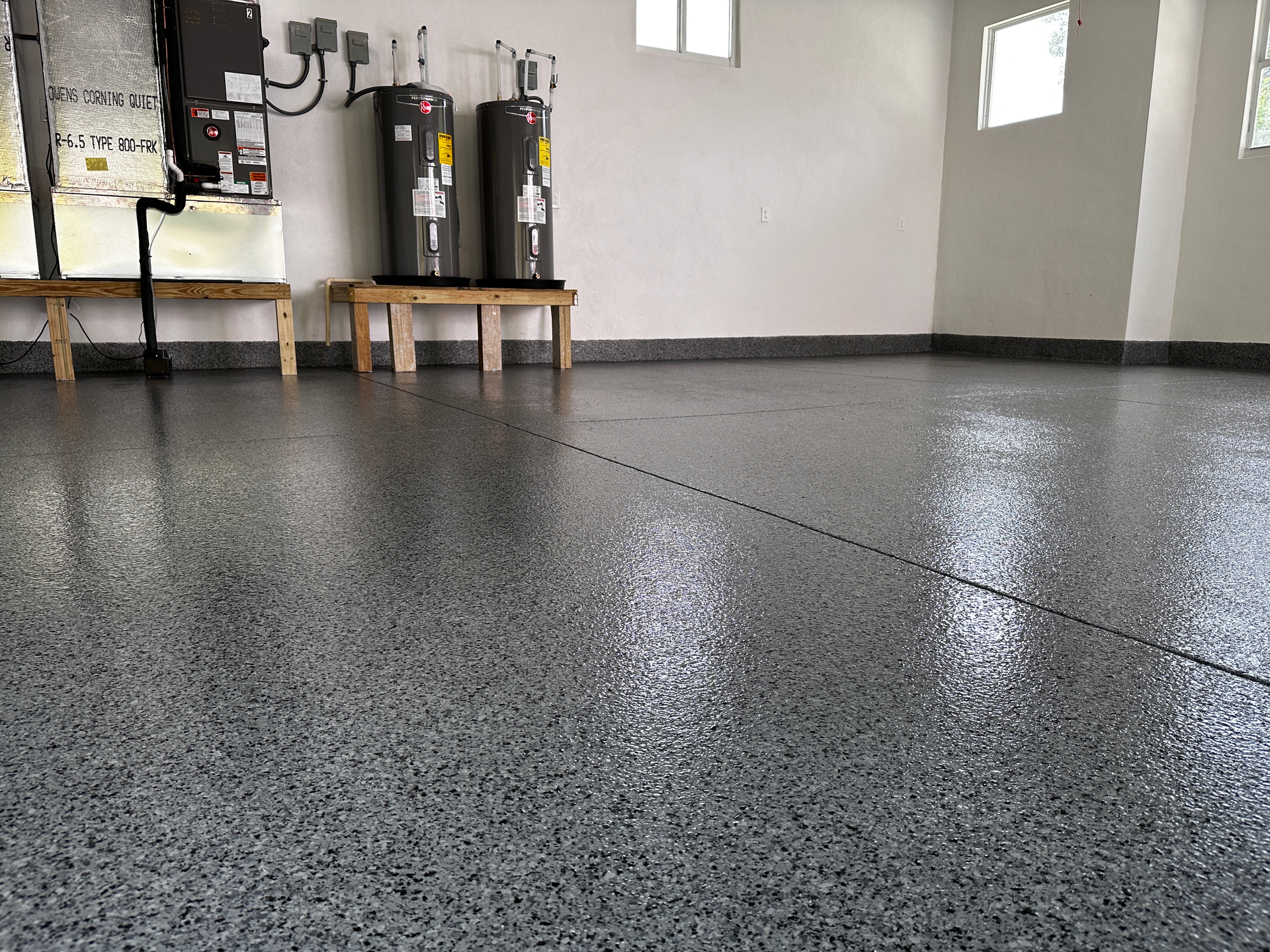 Two water heaters are sitting on a bench in a garage.