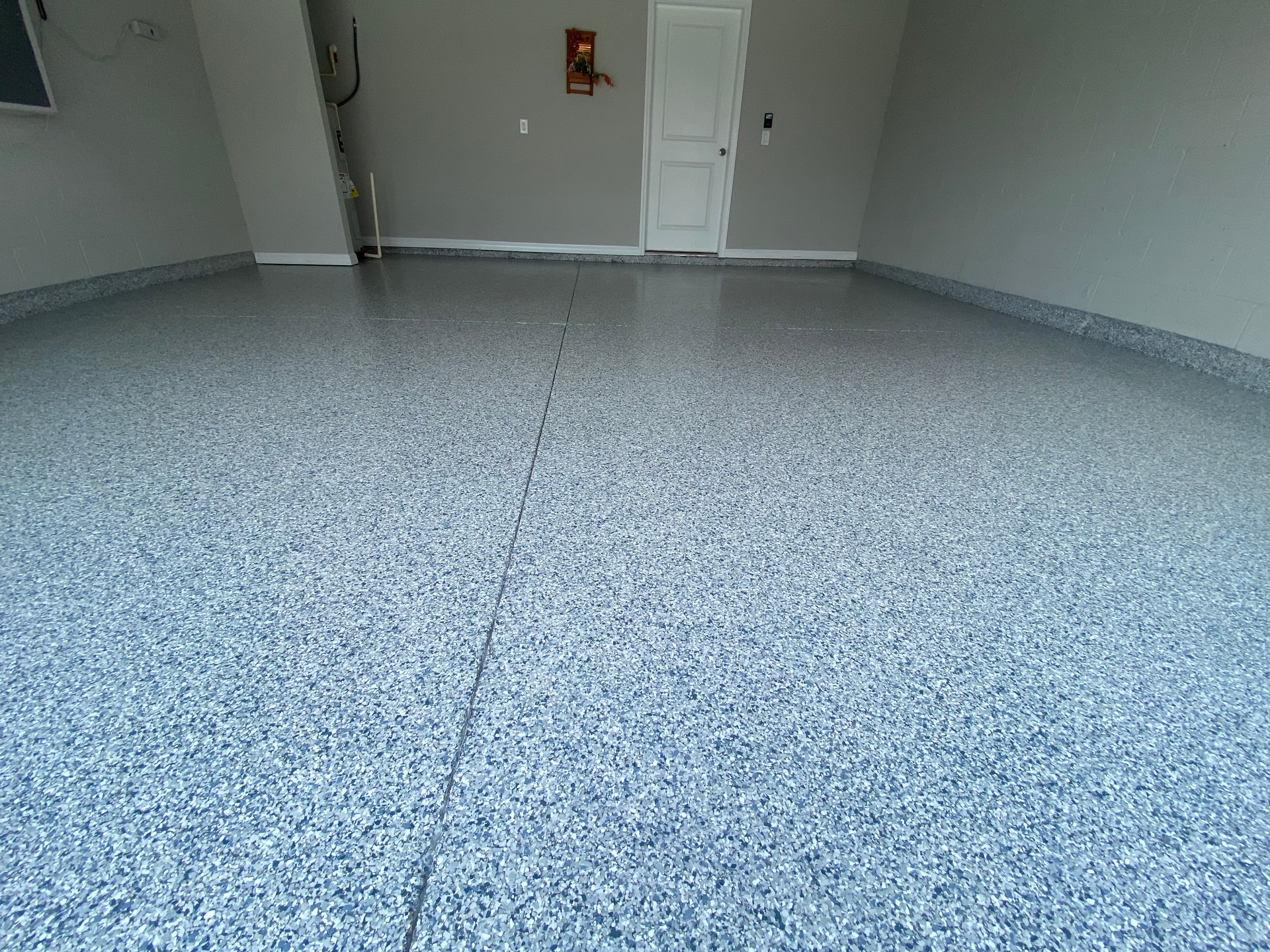 A garage with a gray floor and a white door.