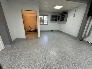 A room with a gray floor and a door leading to a bathroom.