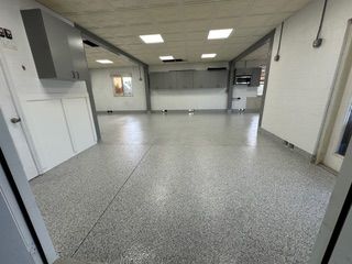 A large room with a gray floor and white cabinets.