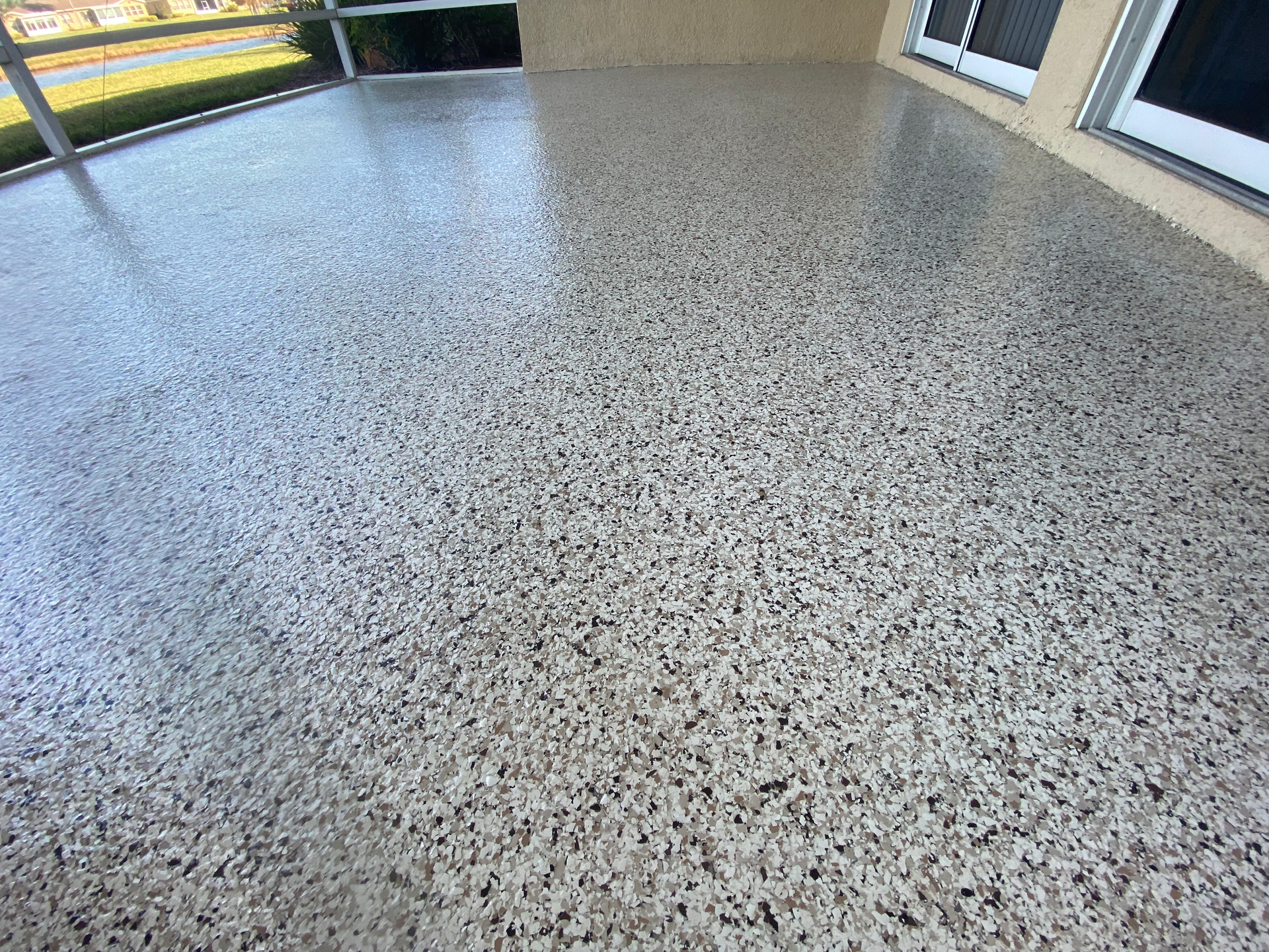 A balcony with a concrete floor and sliding glass doors.