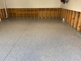 A garage with a gray floor and wooden walls.
