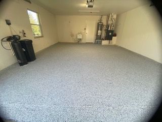 A large empty garage with a gray floor and white walls.