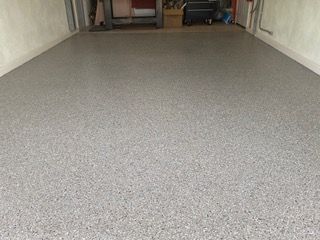 A garage with a gray floor and a white wall.