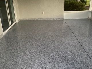 A patio with a gray concrete floor and a sliding glass door.