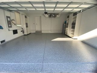A garage with a gray floor and white cabinets.