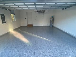 An empty garage with a gray floor and white walls.