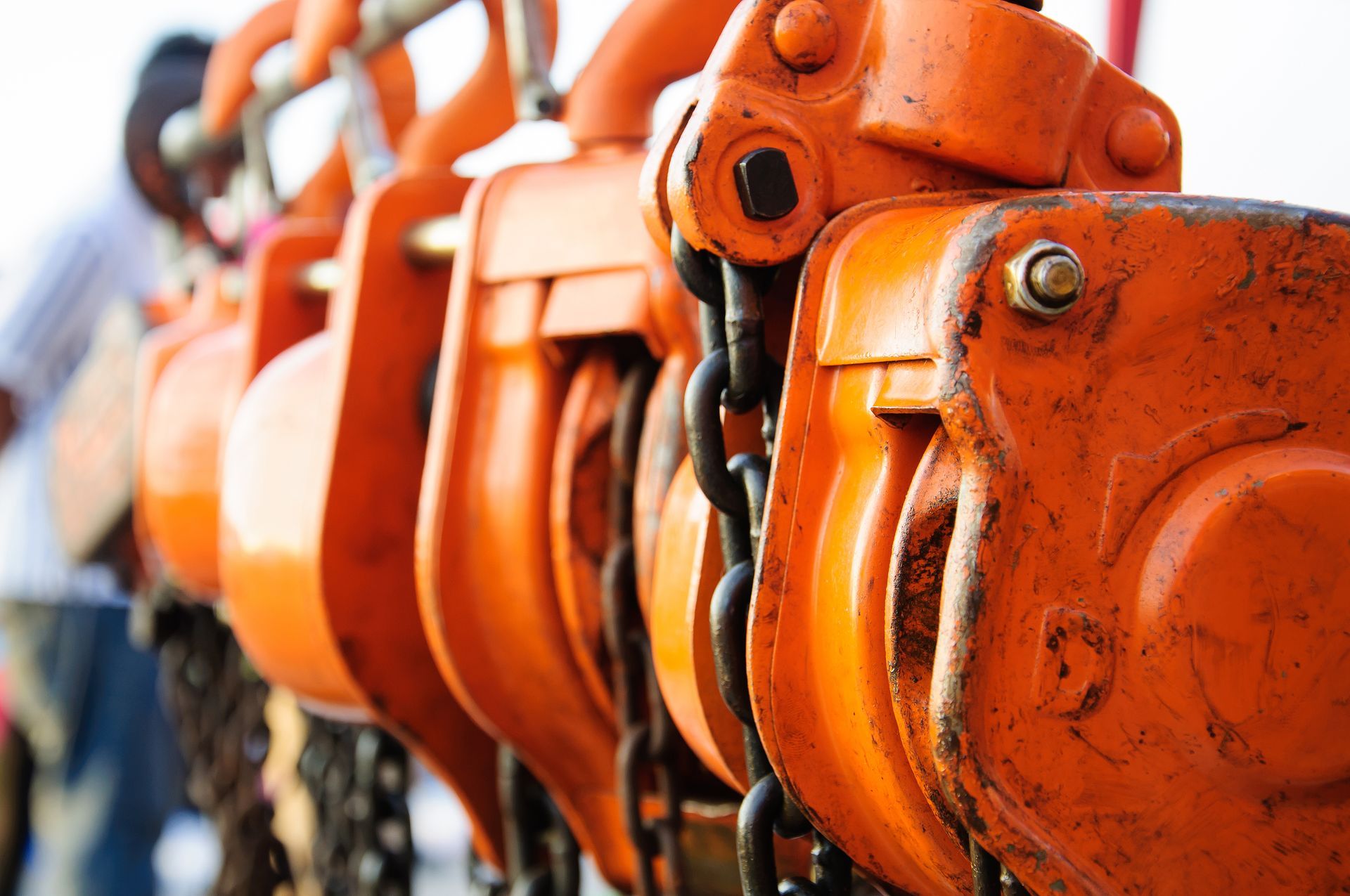 A close up of a row of orange chain hoists.