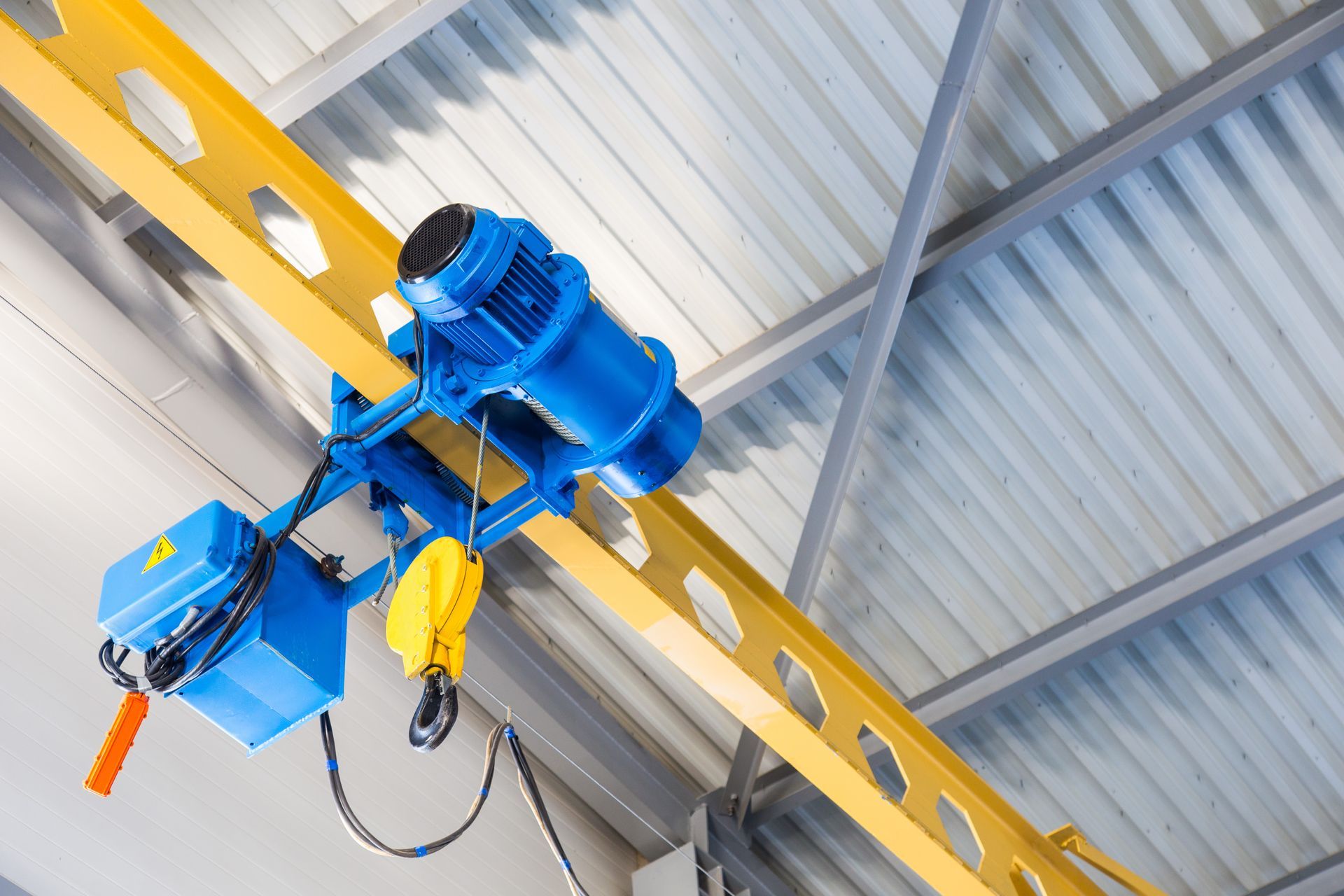 A blue crane is hanging from the ceiling of a building.