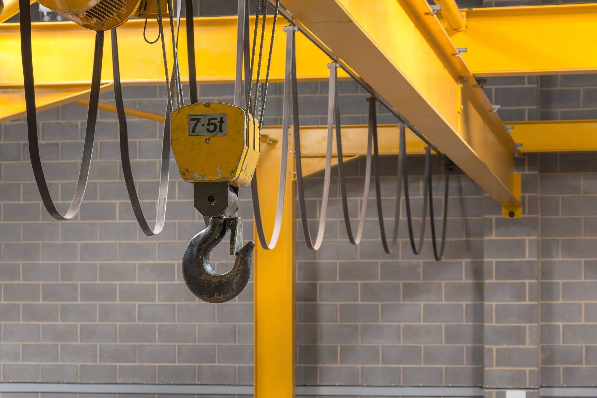 A yellow crane hook is hanging from the ceiling of a building.