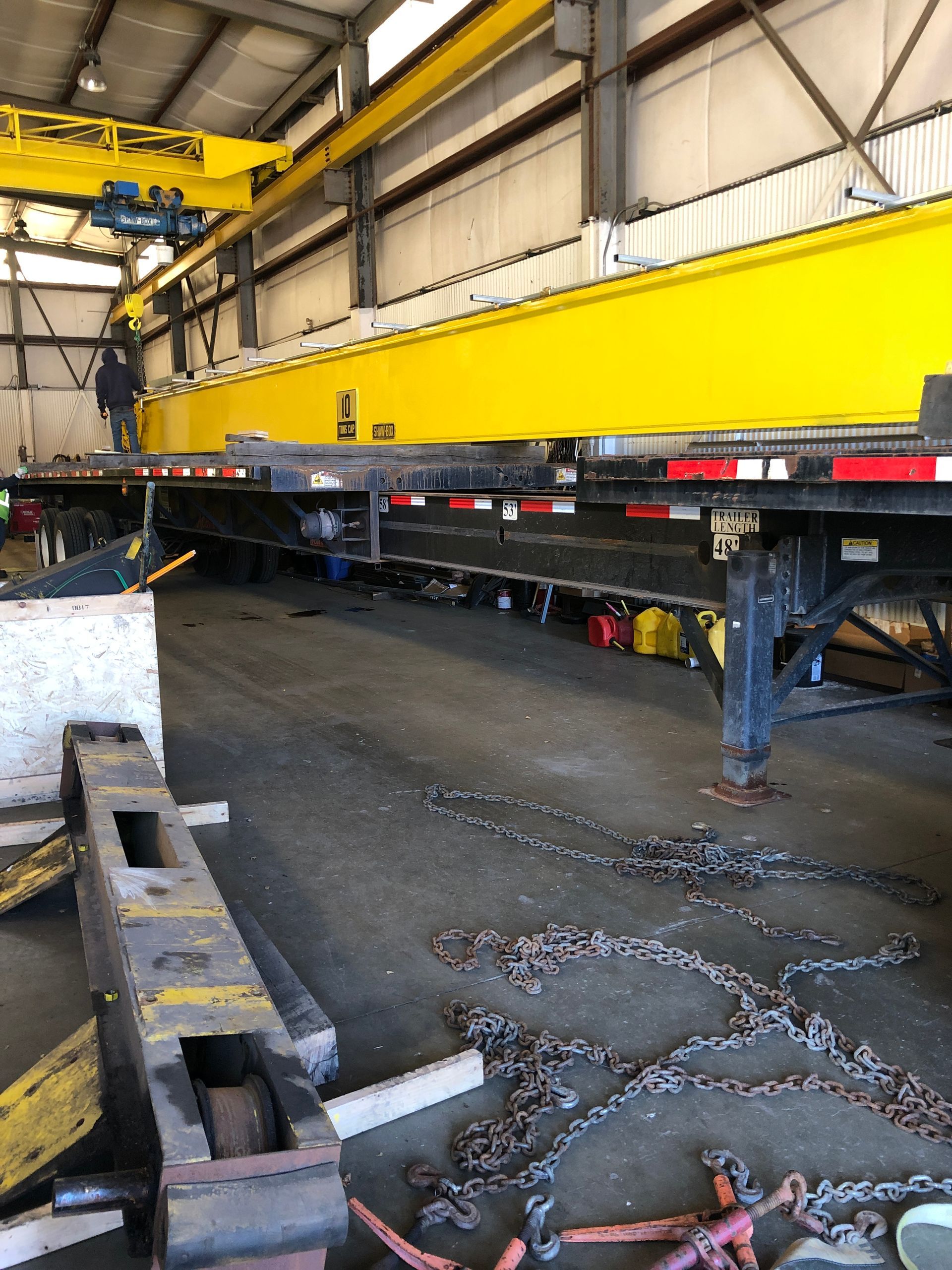 A large yellow crane is sitting on top of a trailer in a warehouse.