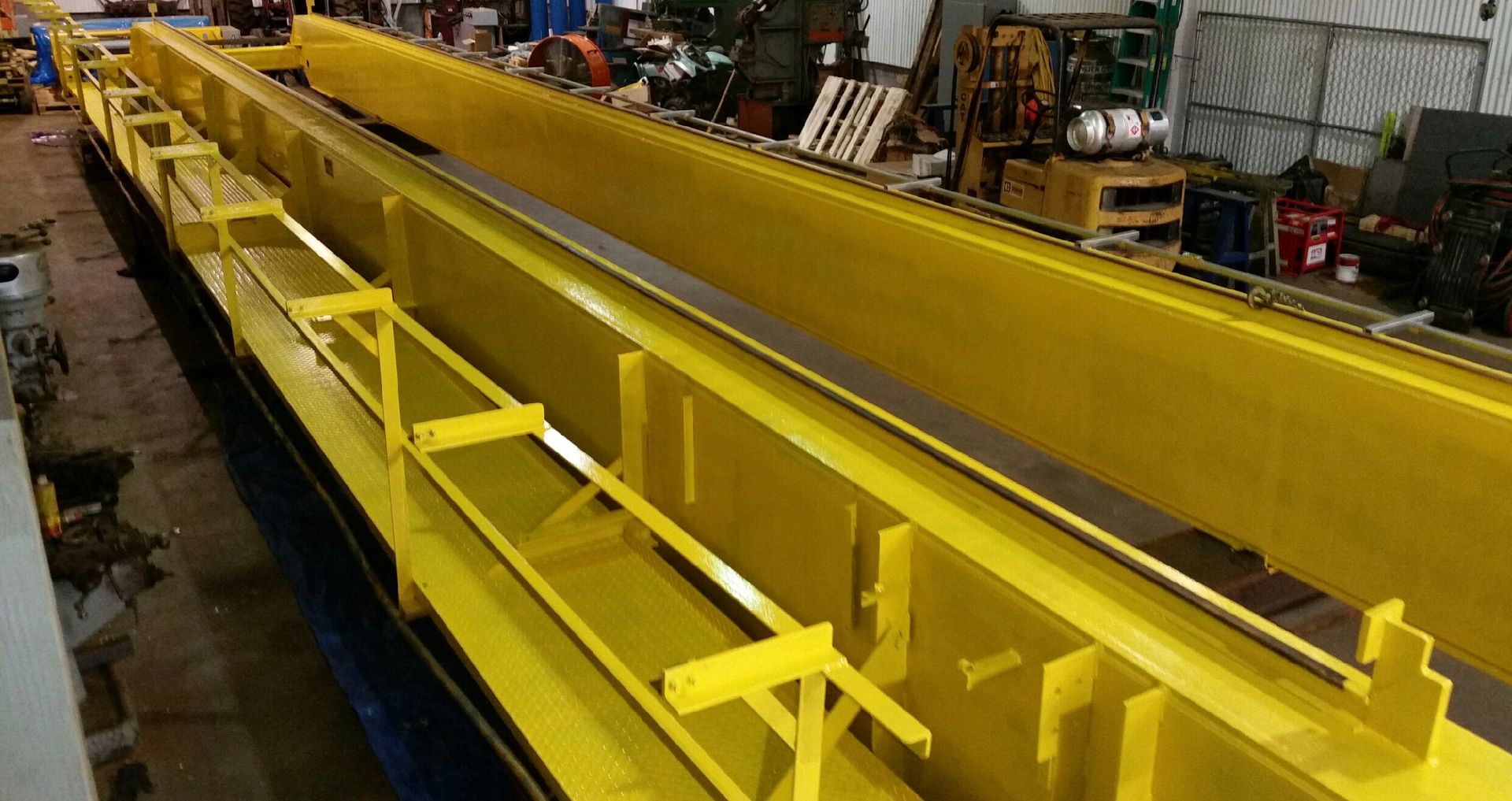 A large yellow crane is sitting in a factory.