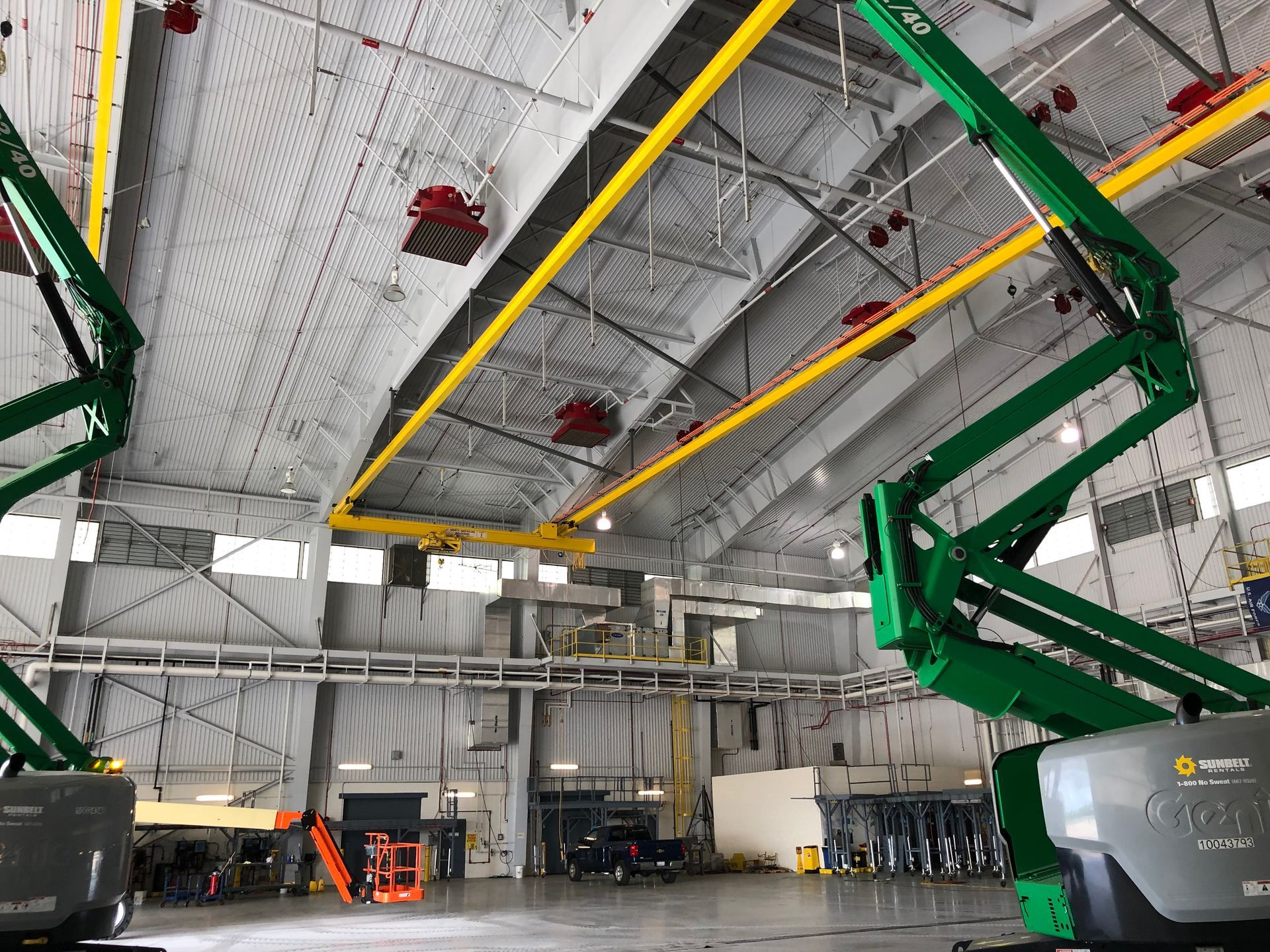 A green crane is sitting in the middle of a large warehouse.