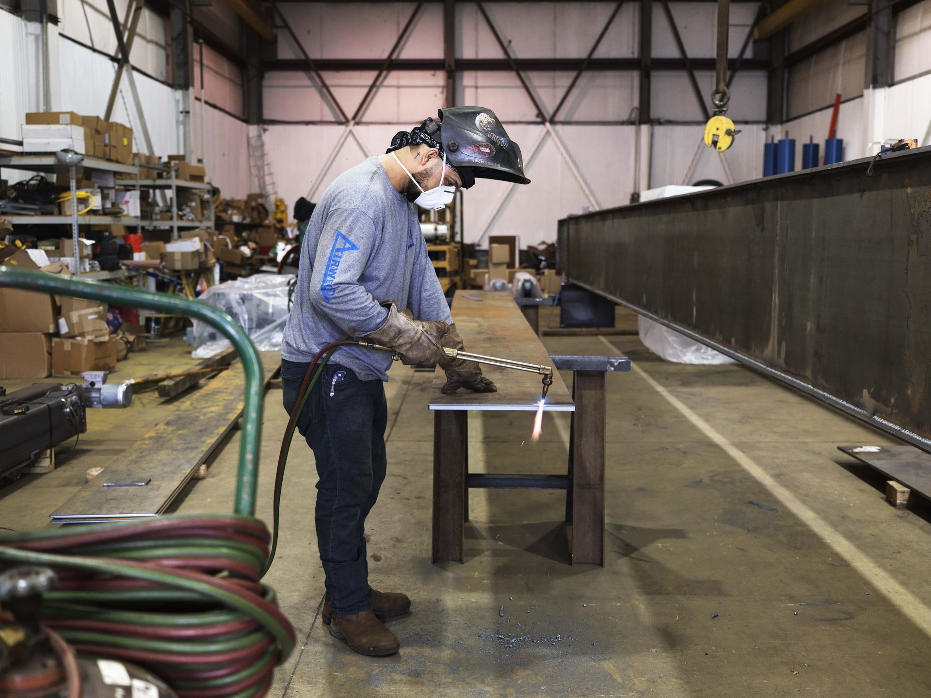 A man wearing a welding helmet is working on a piece of metal