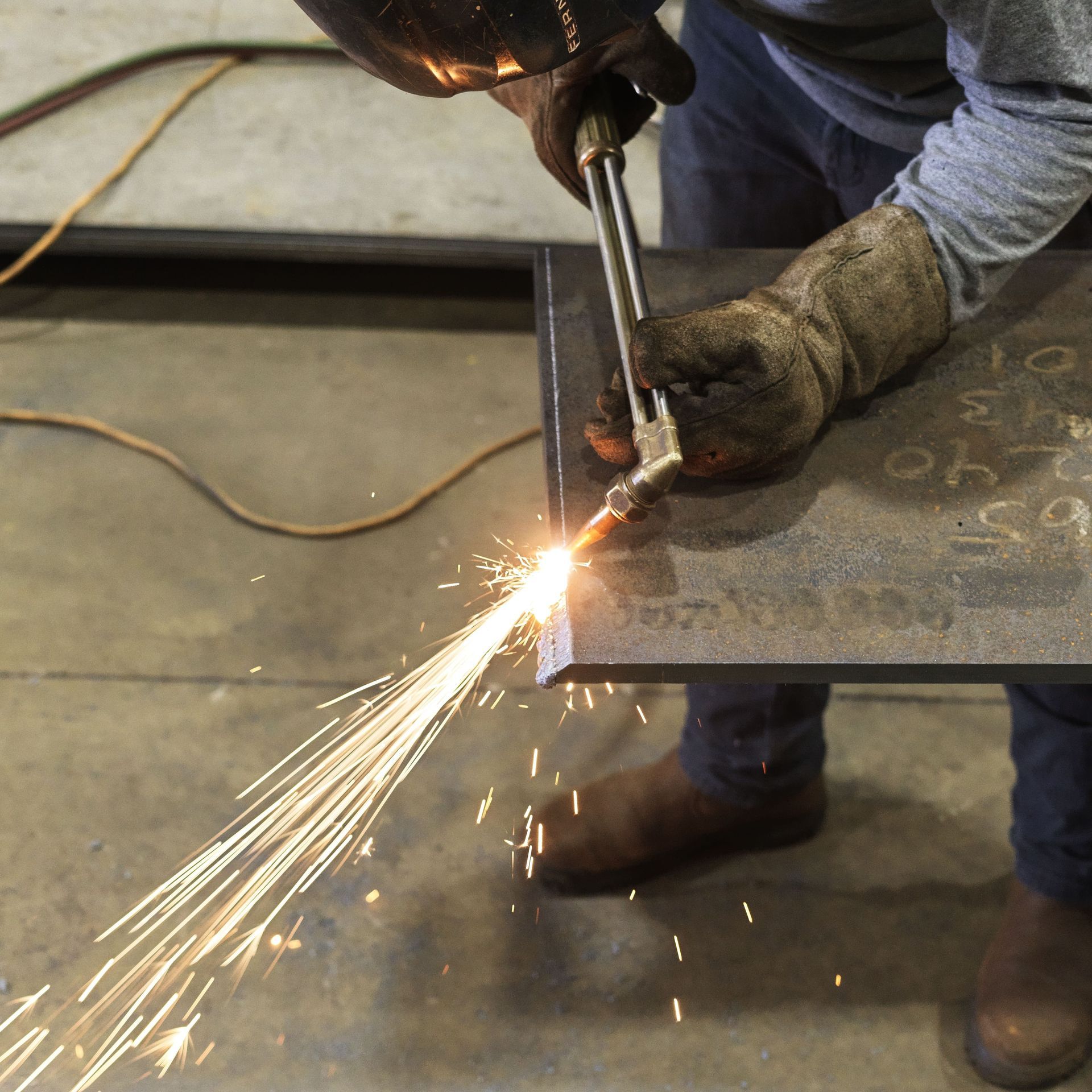 A man is cutting a piece of metal with sparks coming out of it