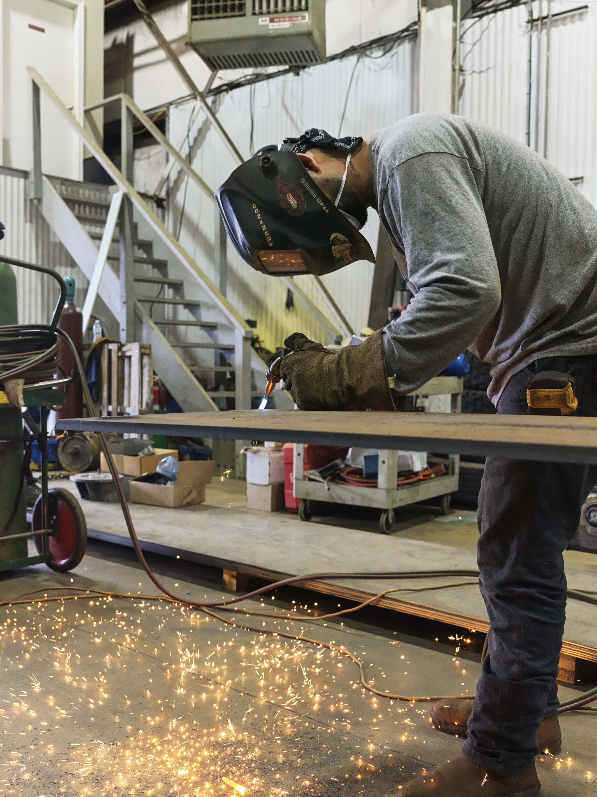A man wearing a welding helmet is working on a piece of metal