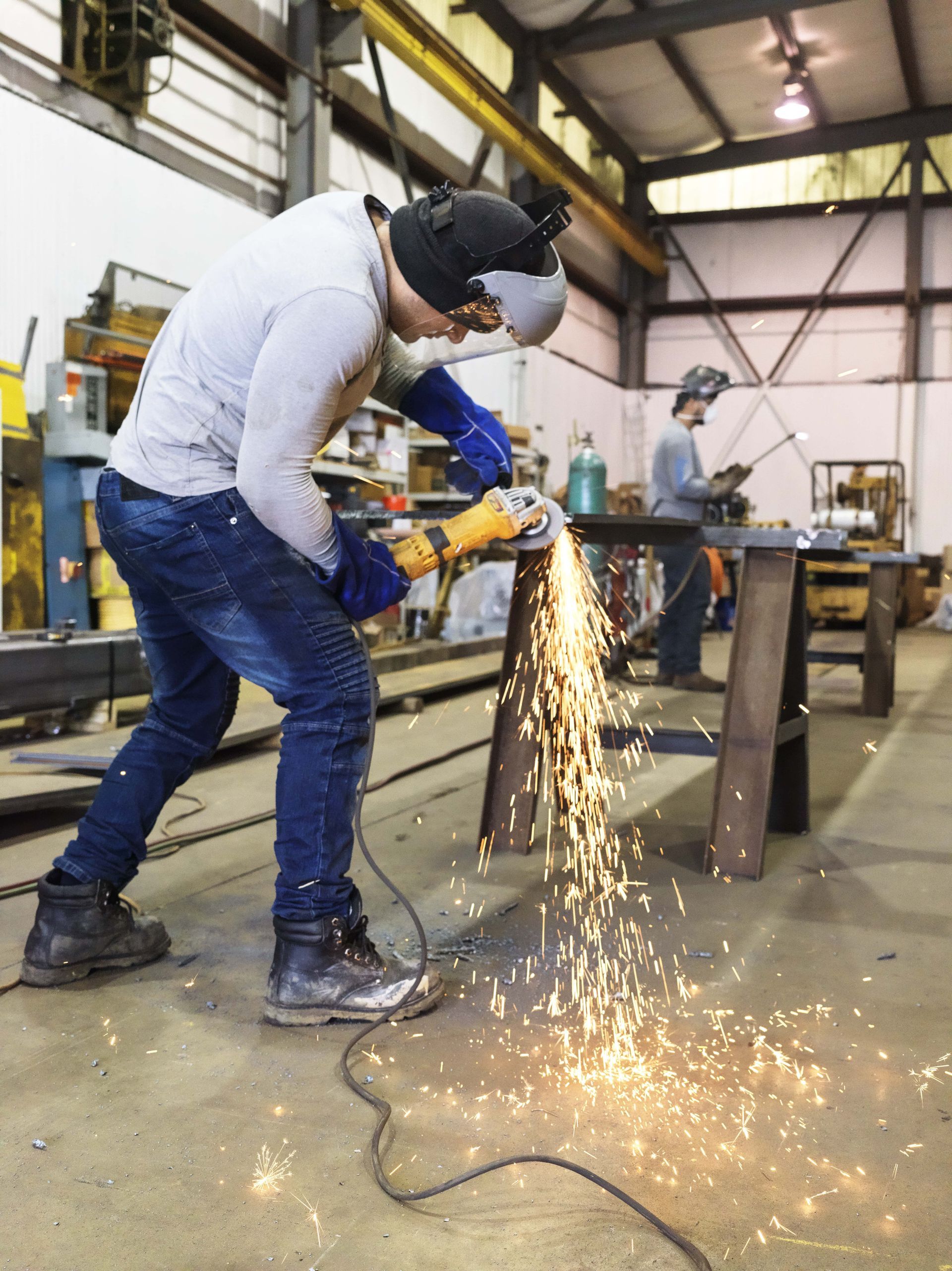 A man is grinding a piece of metal in a factory