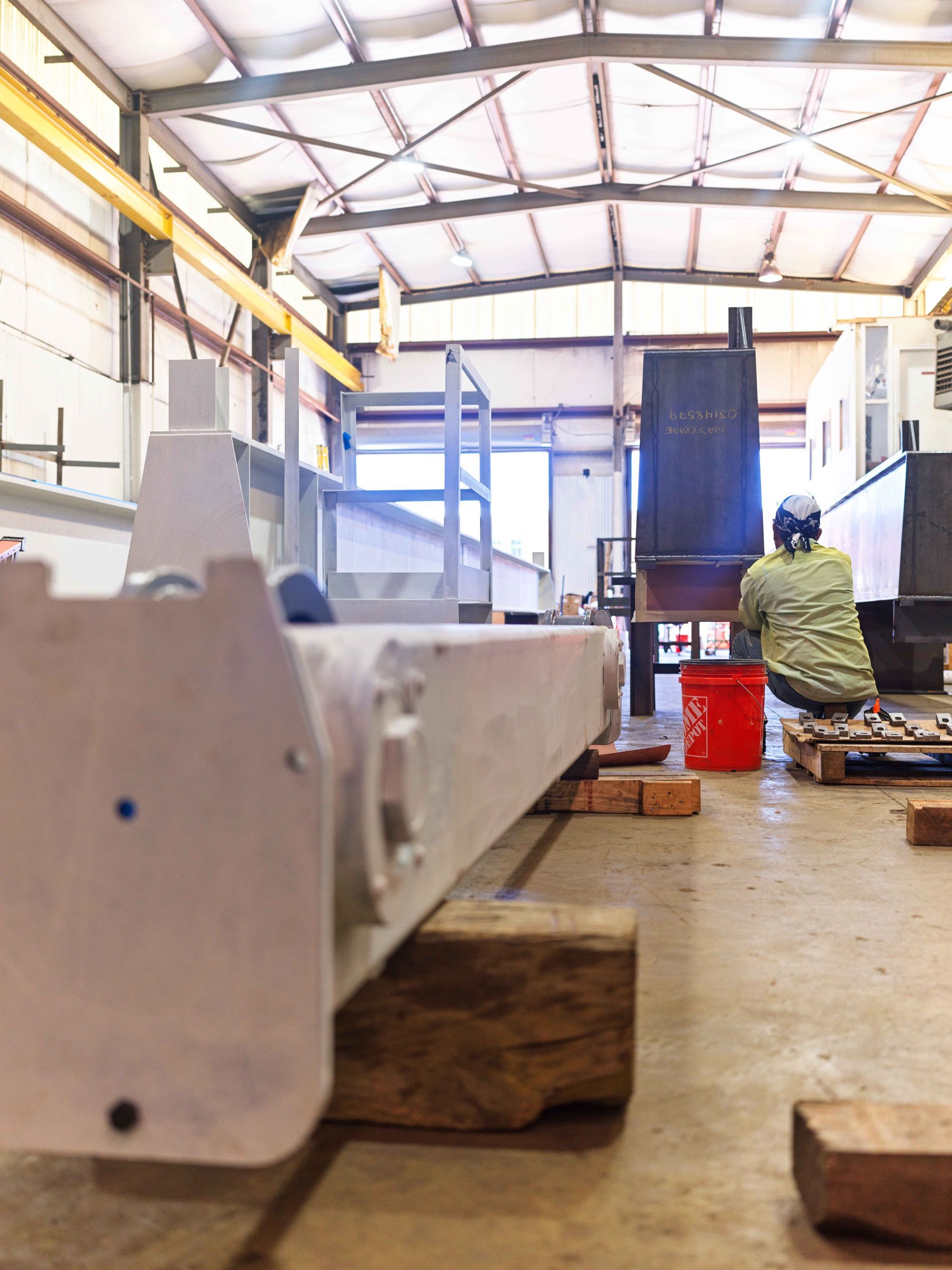 A man is sitting on the floor in a factory working on a machine