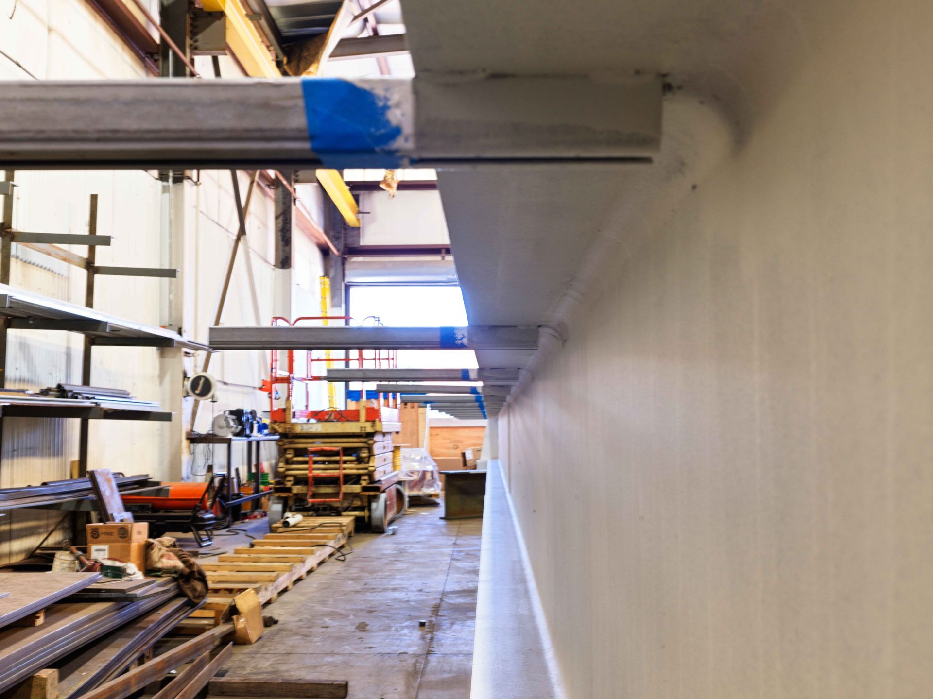 A large white wall in a factory with a blue stripe on it.