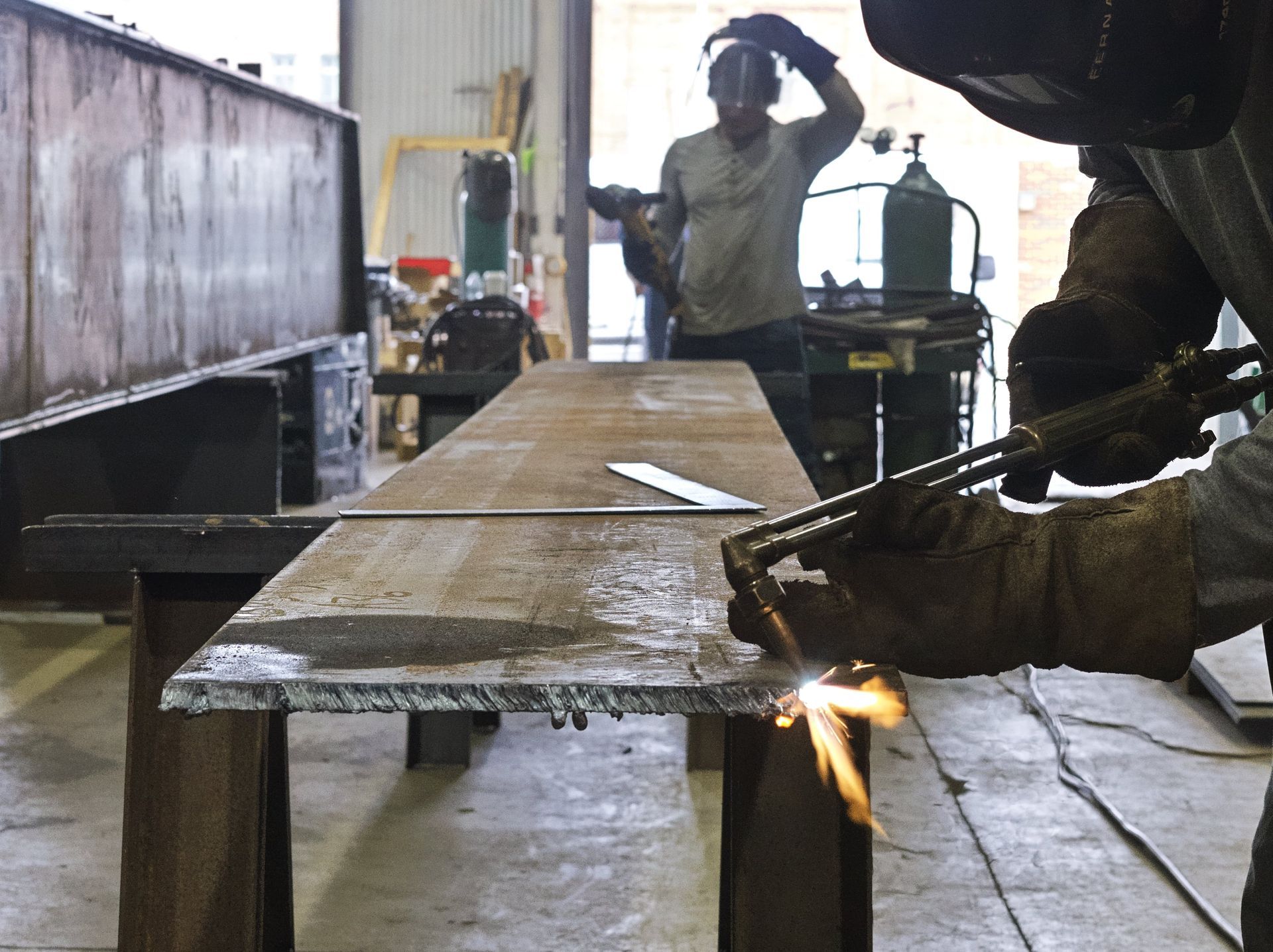 A man is welding a piece of metal in a factory