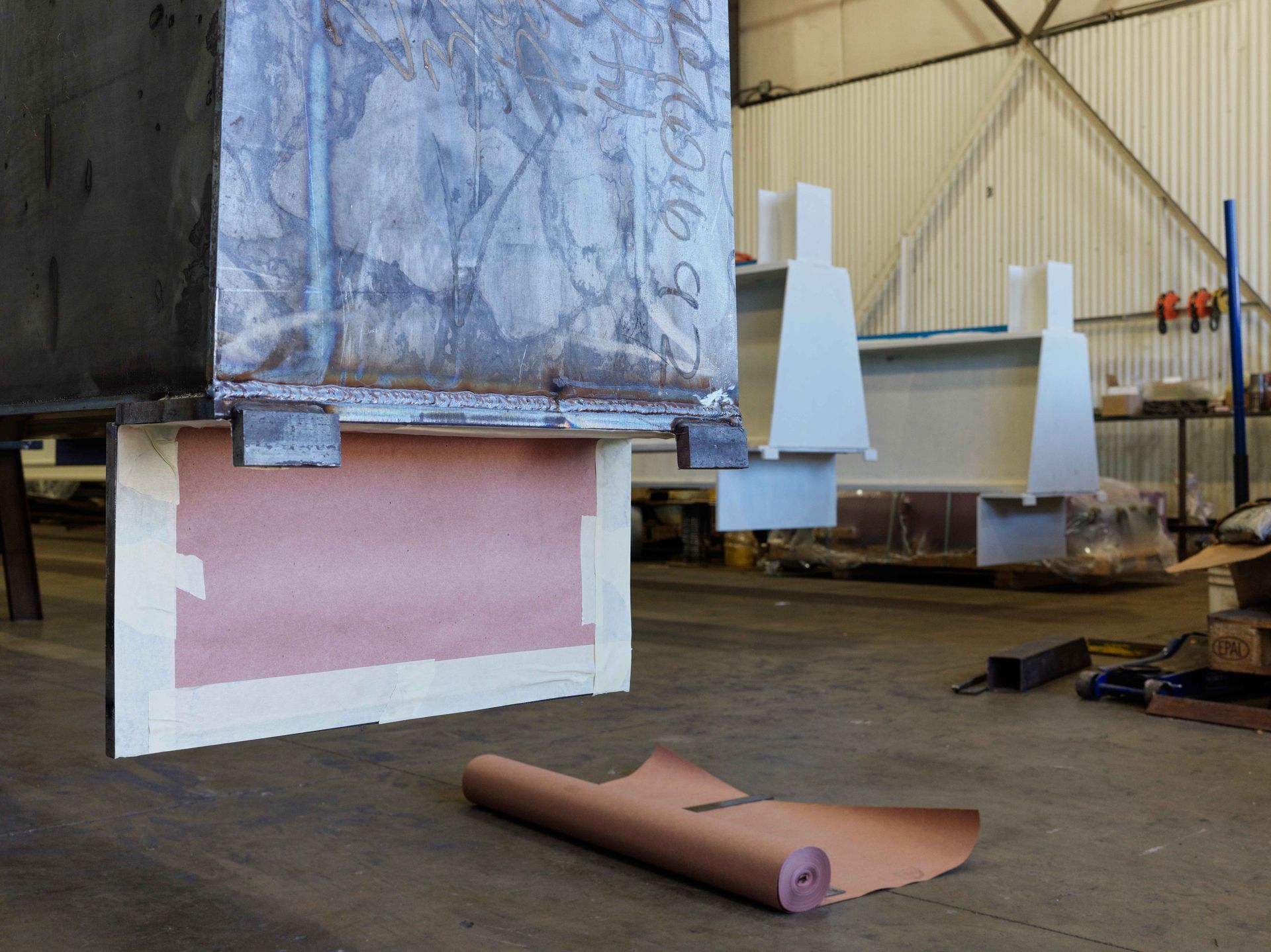 A piece of paper is laying on the floor next to a piece of metal.