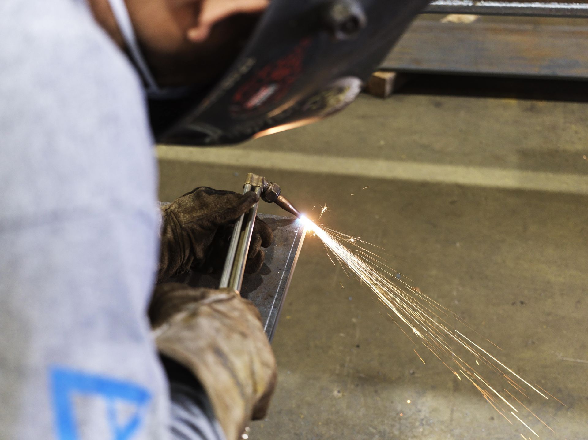 A man wearing a welding helmet is welding a piece of metal
