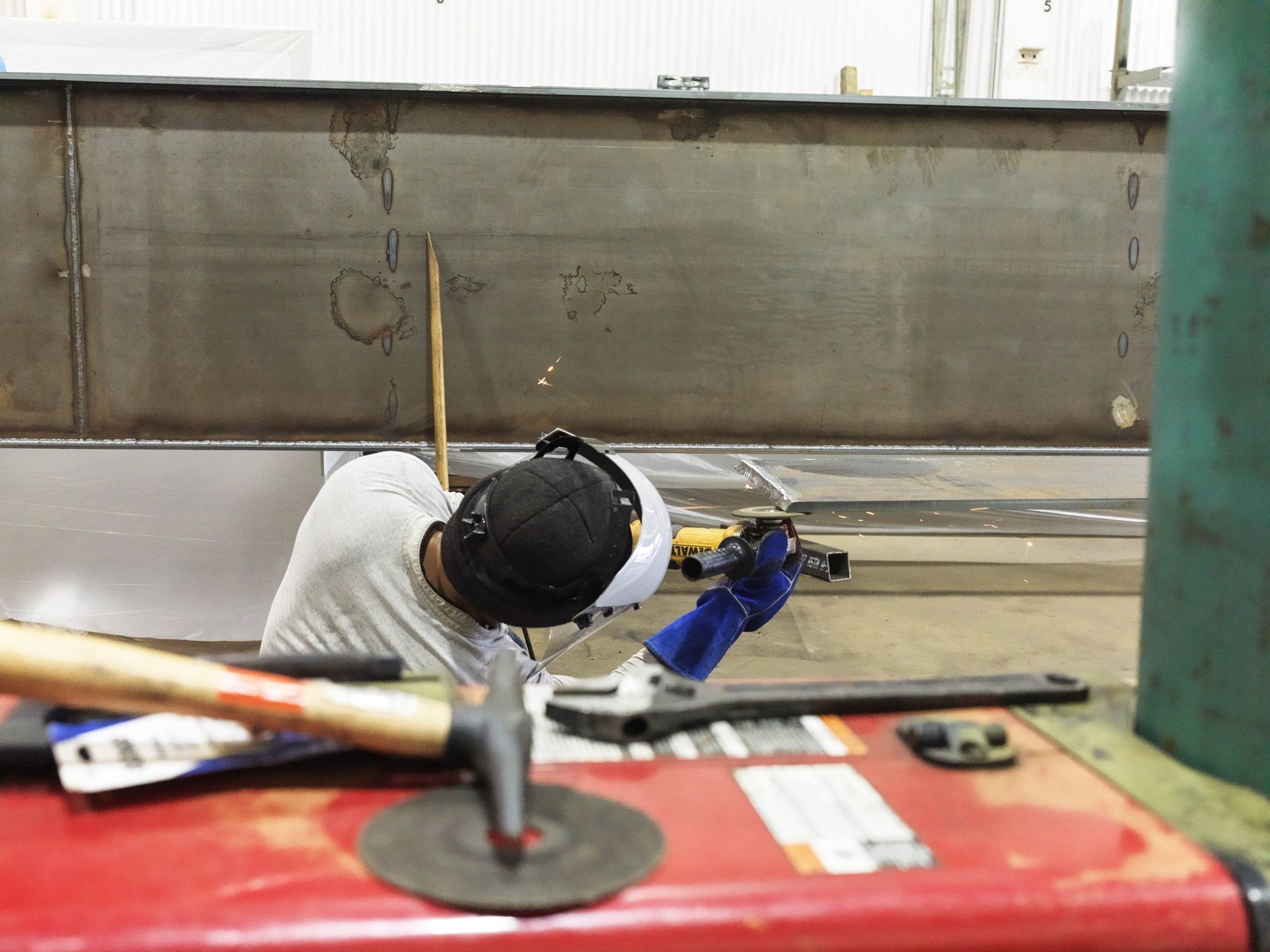 A man wearing headphones is working on a piece of metal.