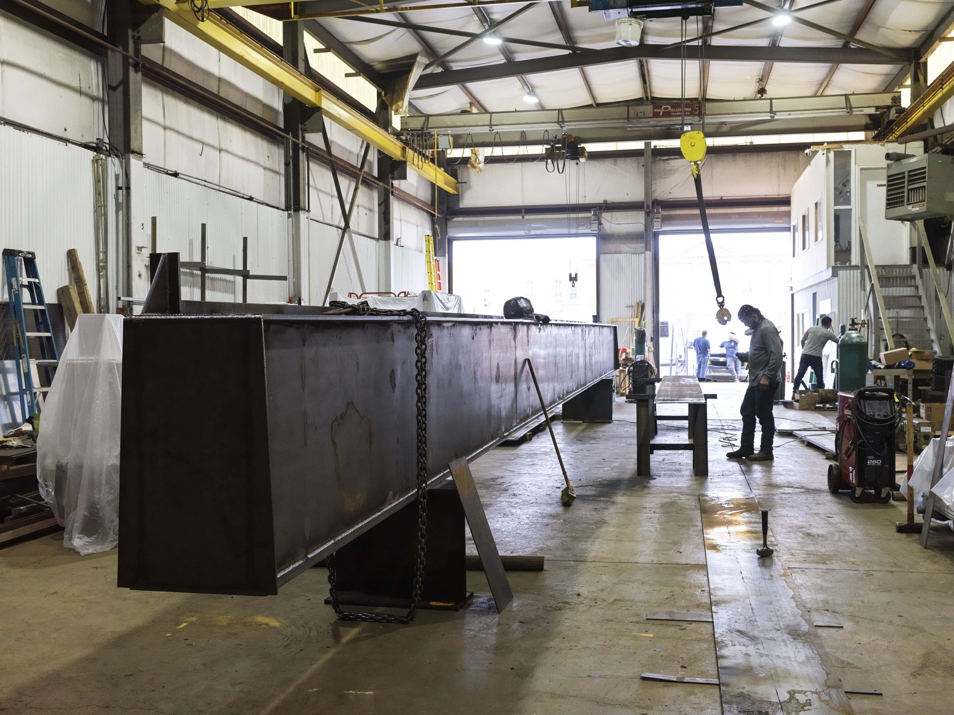 A man is working on a large piece of metal in a factory.