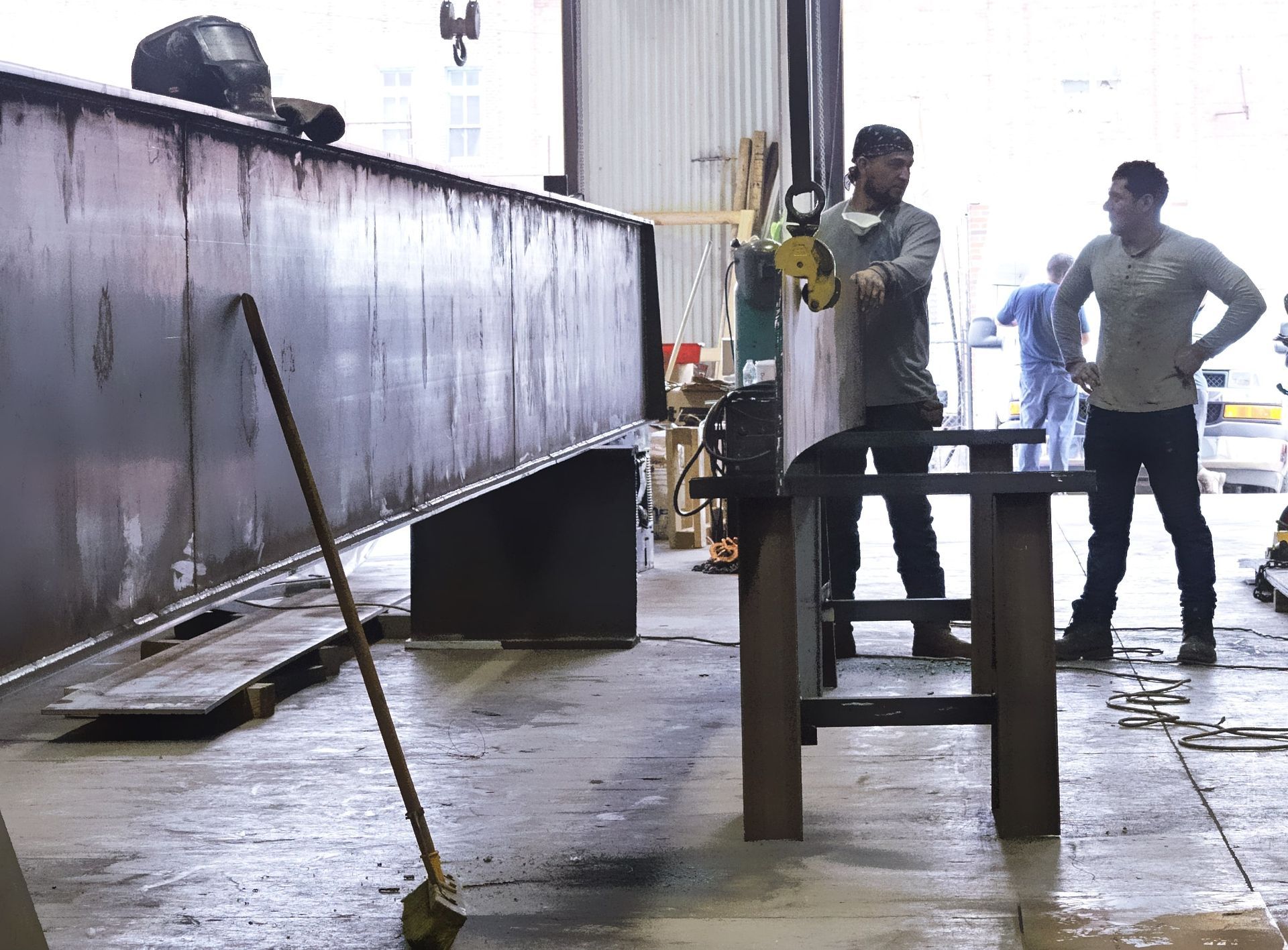 Two men are working on a piece of metal in a factory.