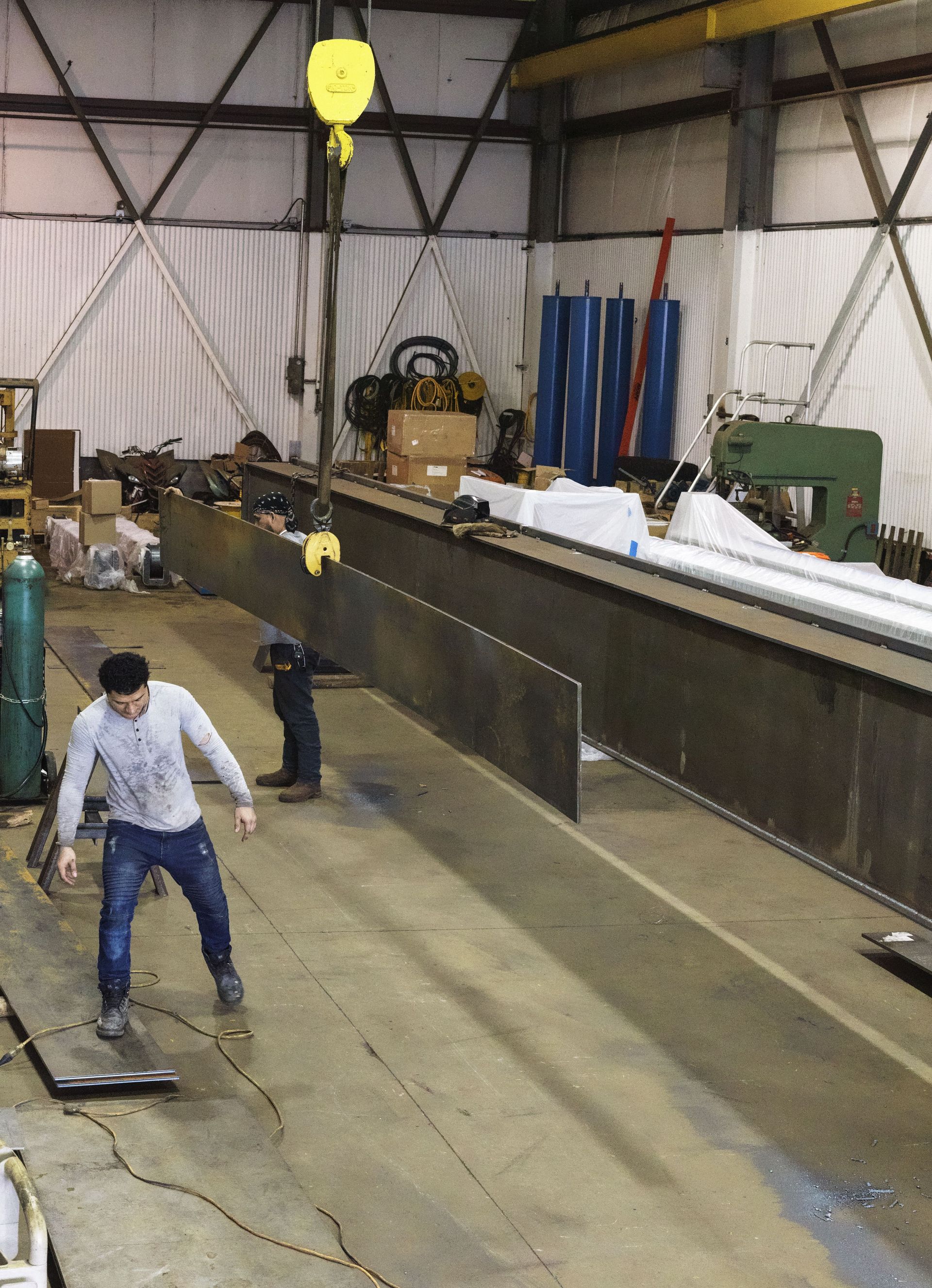A man is standing in front of a crane in a factory