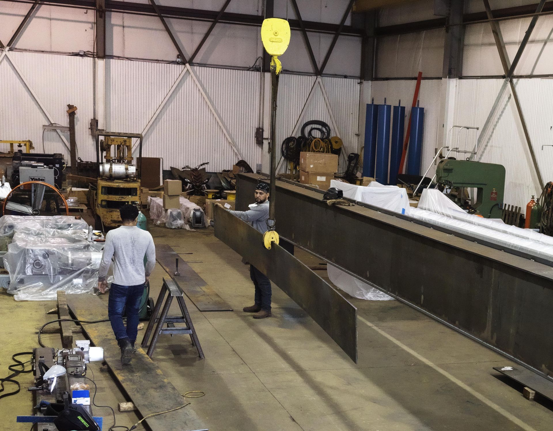 A man is carrying a large piece of metal in a factory