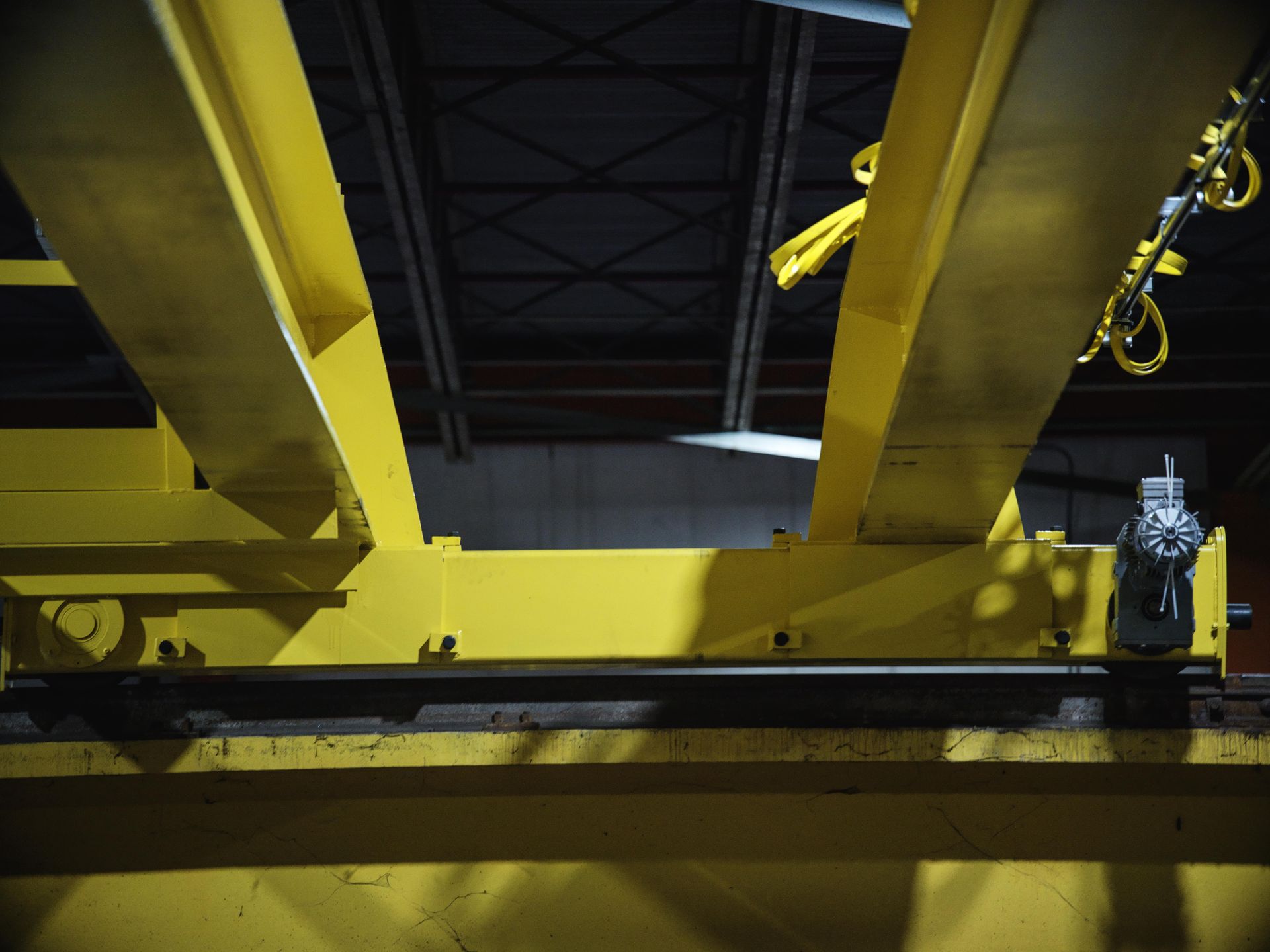 A yellow crane is hanging from the ceiling of a building