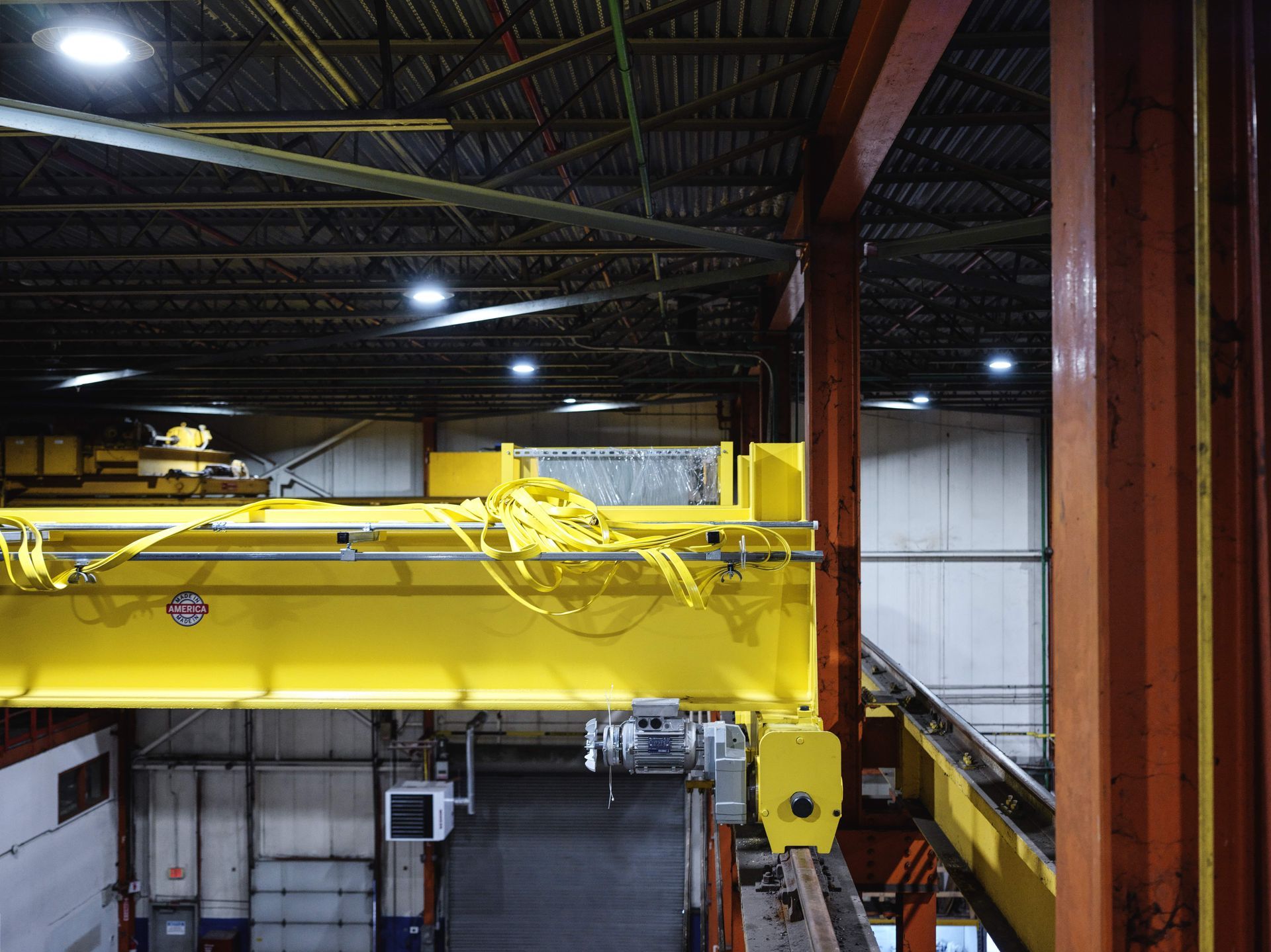 A yellow overhead crane is in a warehouse