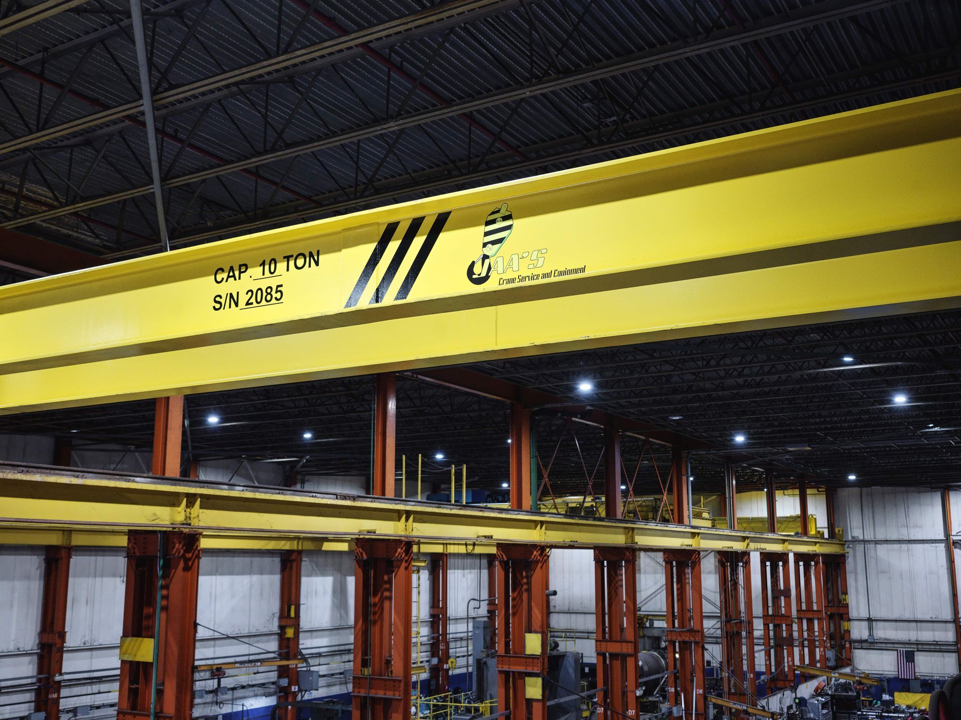 A large yellow crane is hanging from the ceiling of a factory