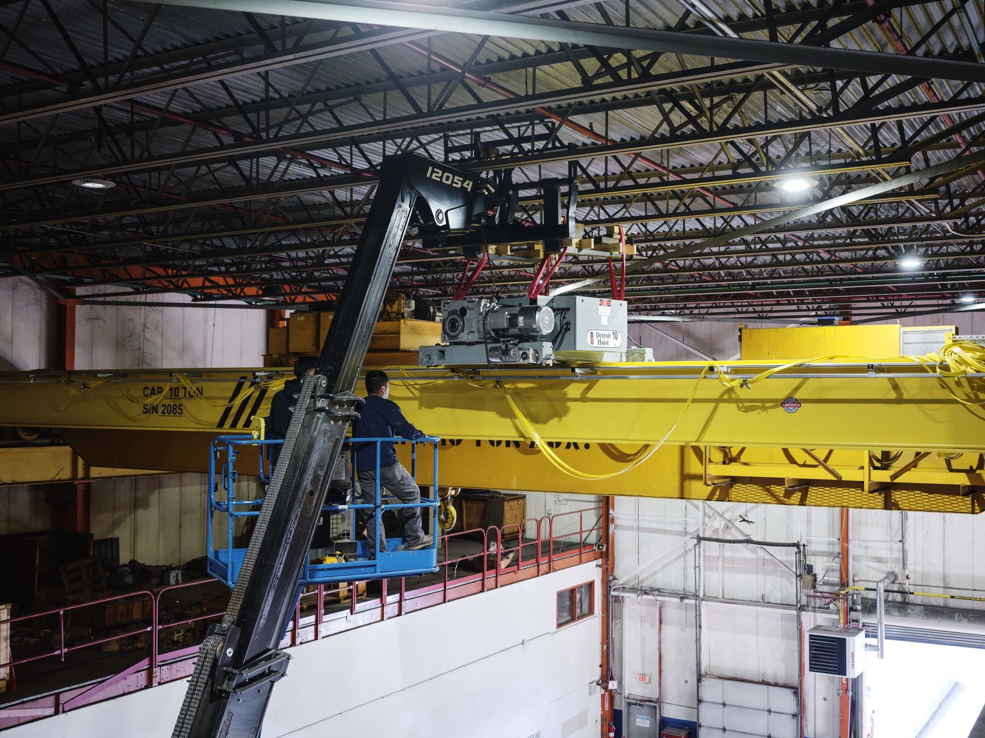 A man is working on a crane in a warehouse