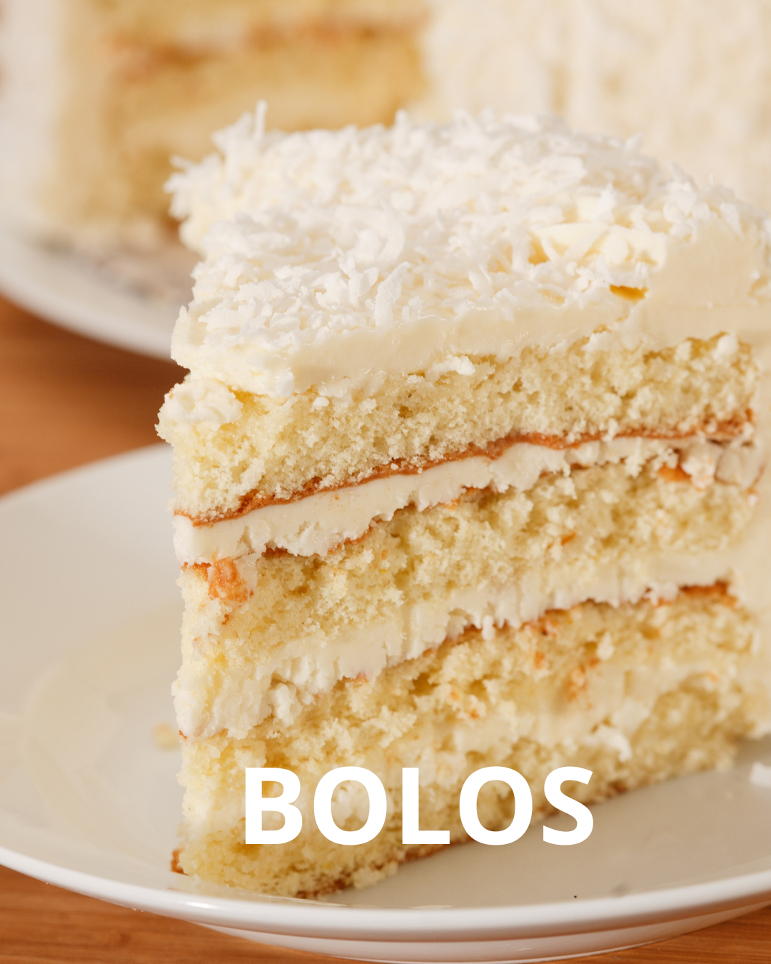 Uma fatia de bolo branco com coco por cima está em um prato branco.