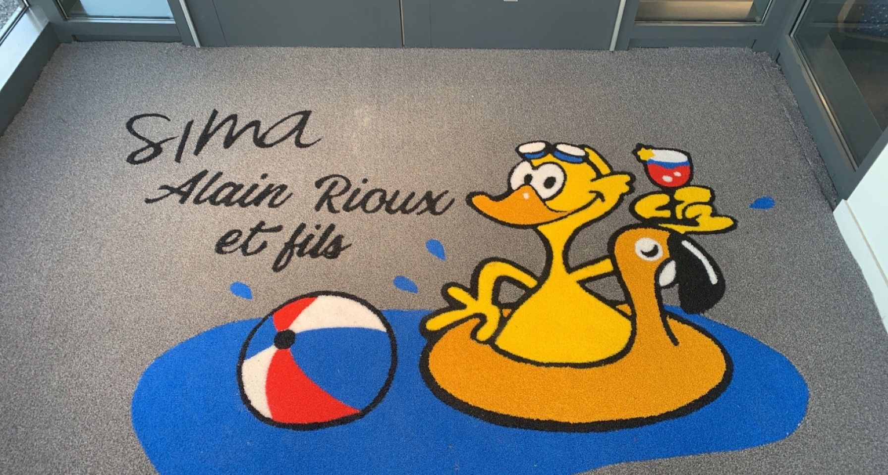 A doormat with a cartoon duck in an inner tube, a beach ball, and text that reads
