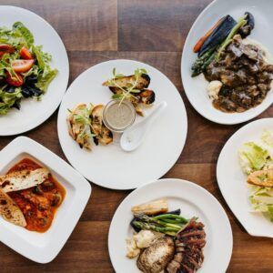 Assorted plated gourmet dishes on a wooden table, seen from above.