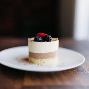 Small layered berry dessert on a white plate on a wooden table