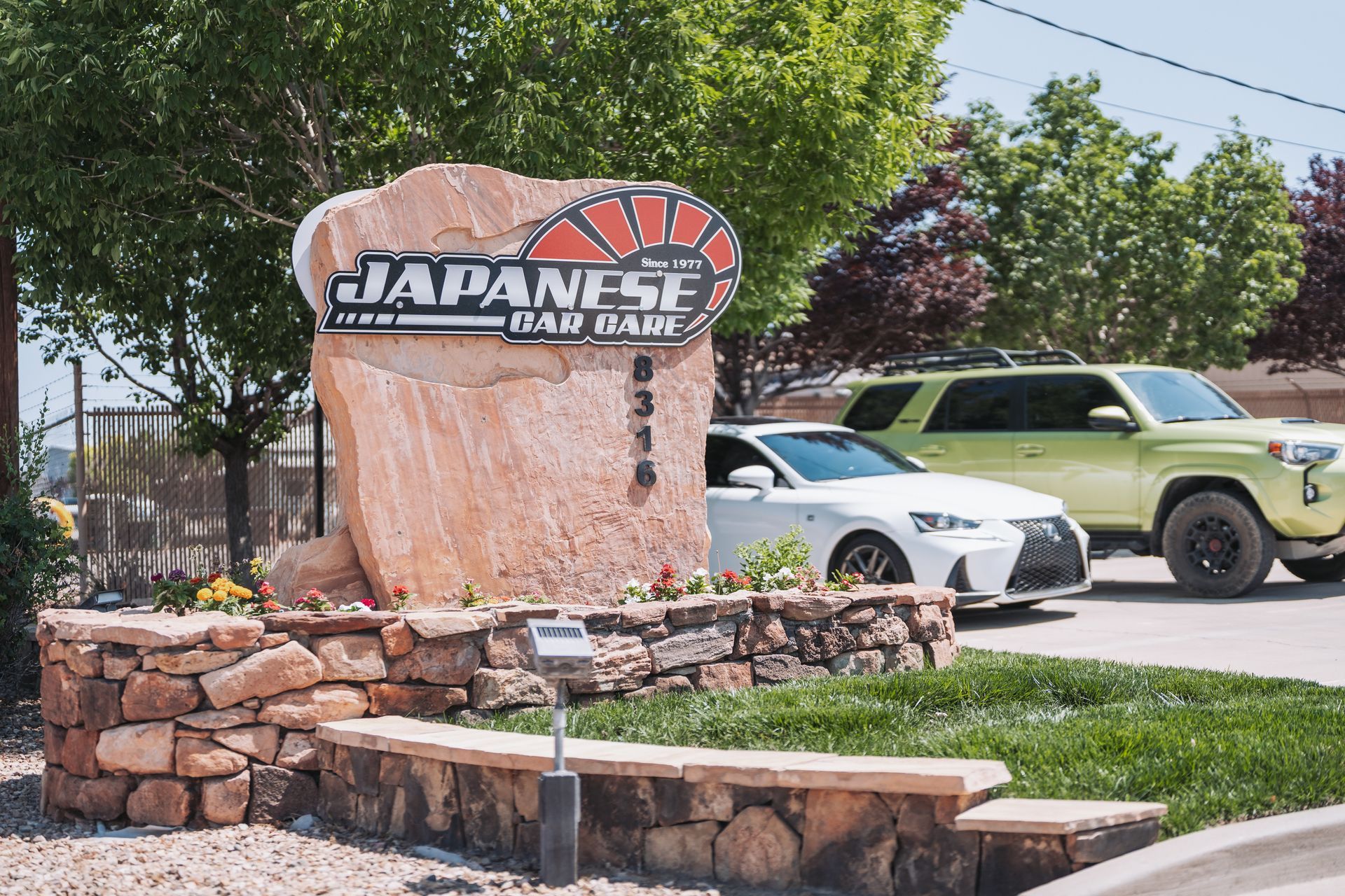 Two cars are parked in front of a japanese car dealership sign. | Japanese Car Care