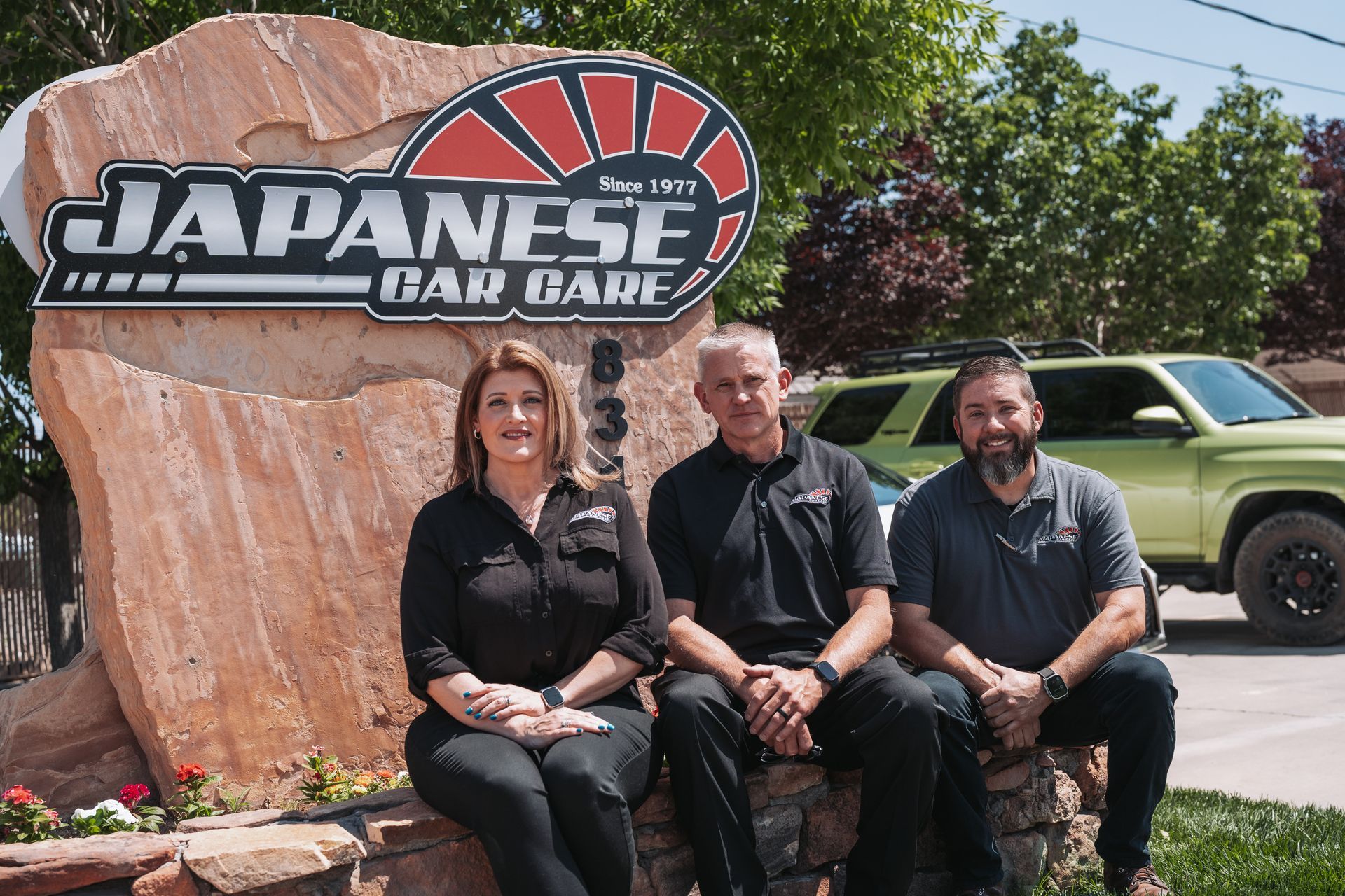 A group of people sitting in front of a japanese car care sign | Japanese Car Care