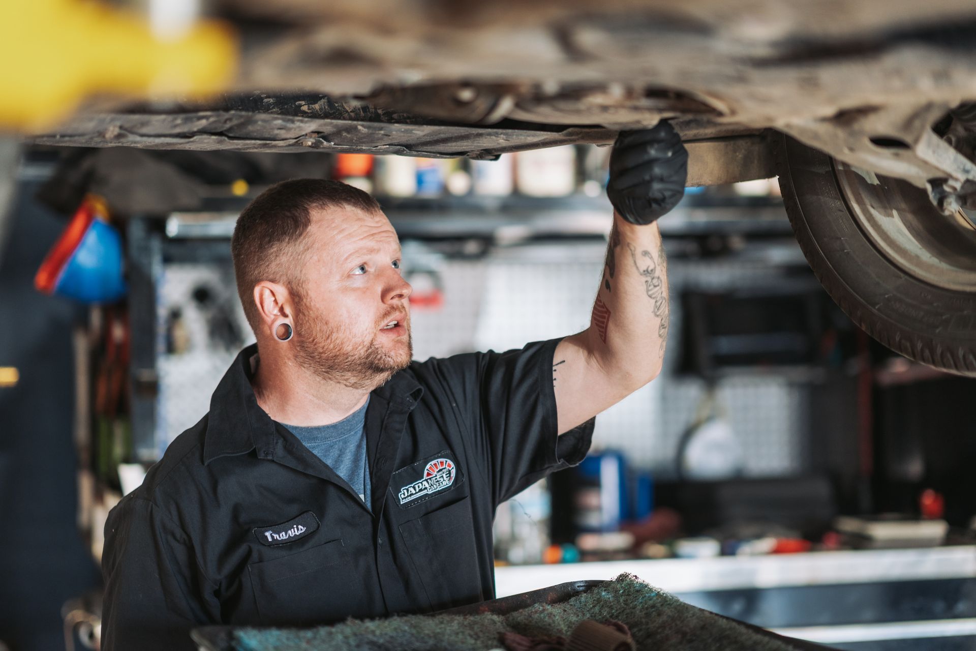 A man is working under a car in a garage. | Japanese Car Care