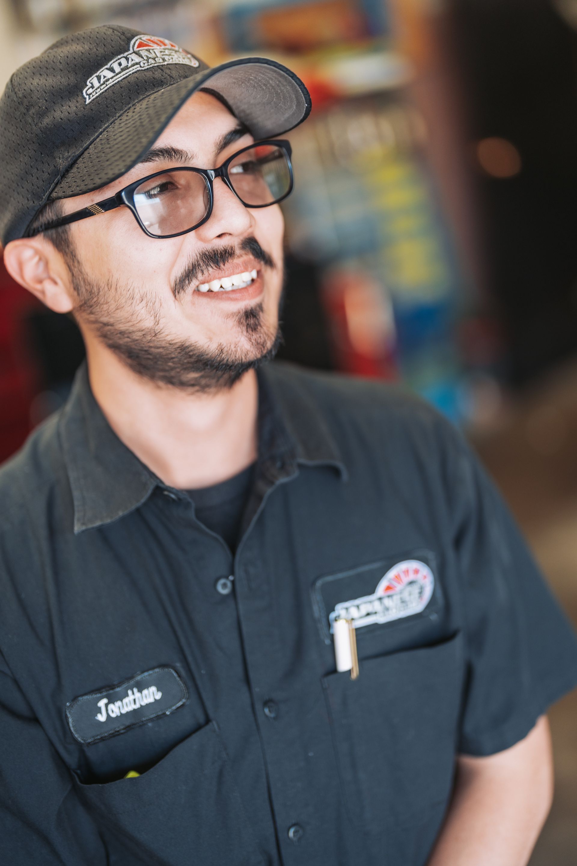 A man wearing a hat and glasses is smiling. | Japanese Car Care