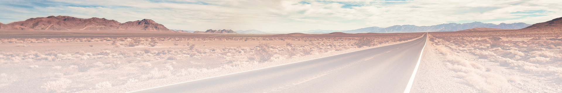 A road going through a desert with mountains in the background. | Japanese Car Care