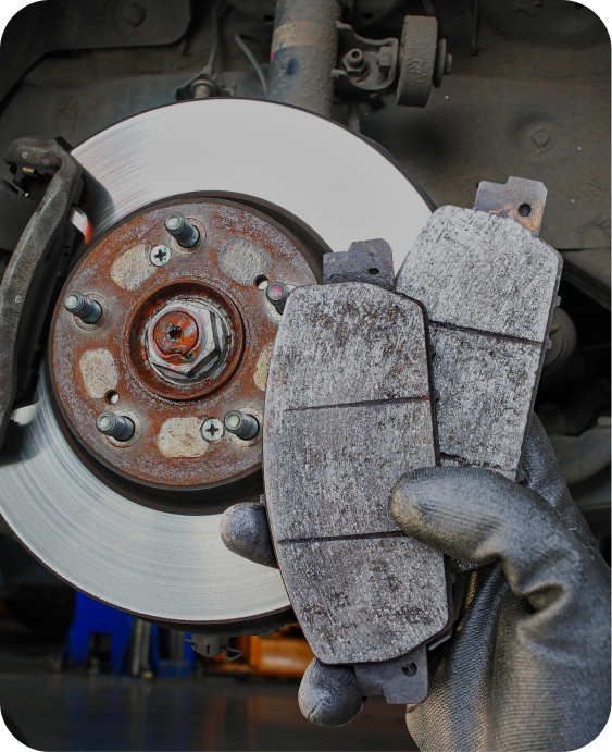A person is holding a pair of brake pads next to a brake disc. | Japanese Car Care