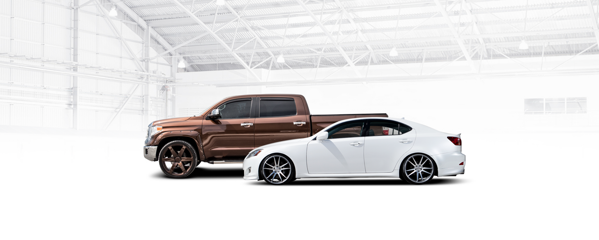 A brown truck and a white car are parked next to each other in a garage. | Japanese Car Care