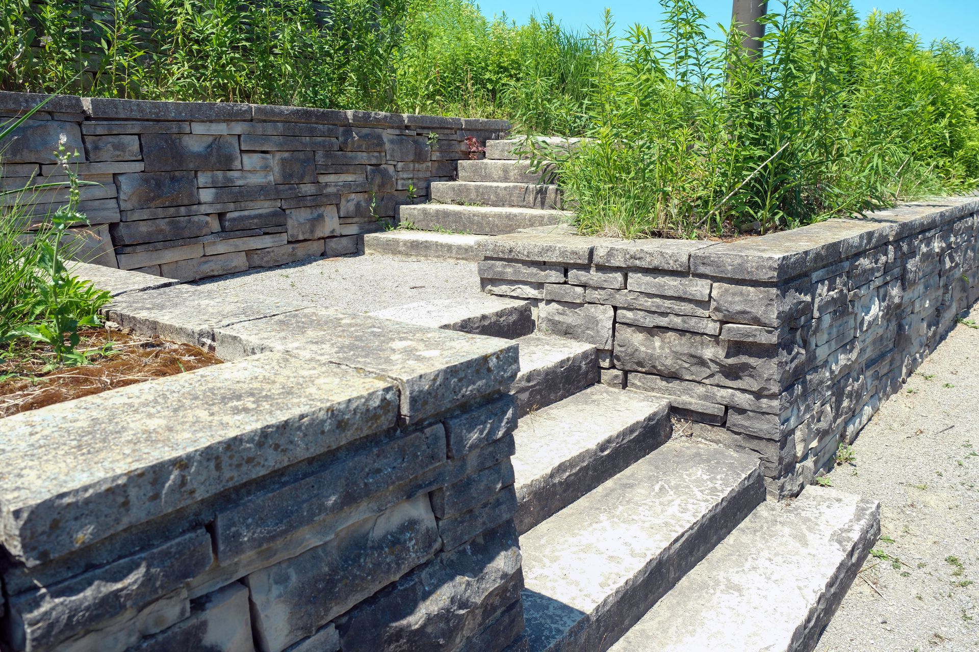 Stone stairs built into a landscaped terrace with retaining walls and surrounding green vegetation.