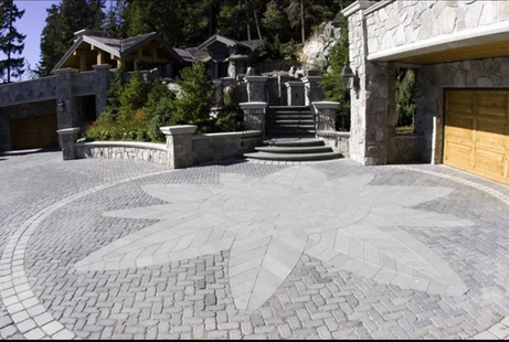 A multi-level stone home with a circular driveway featuring a large, star-shaped stone inlay pattern.